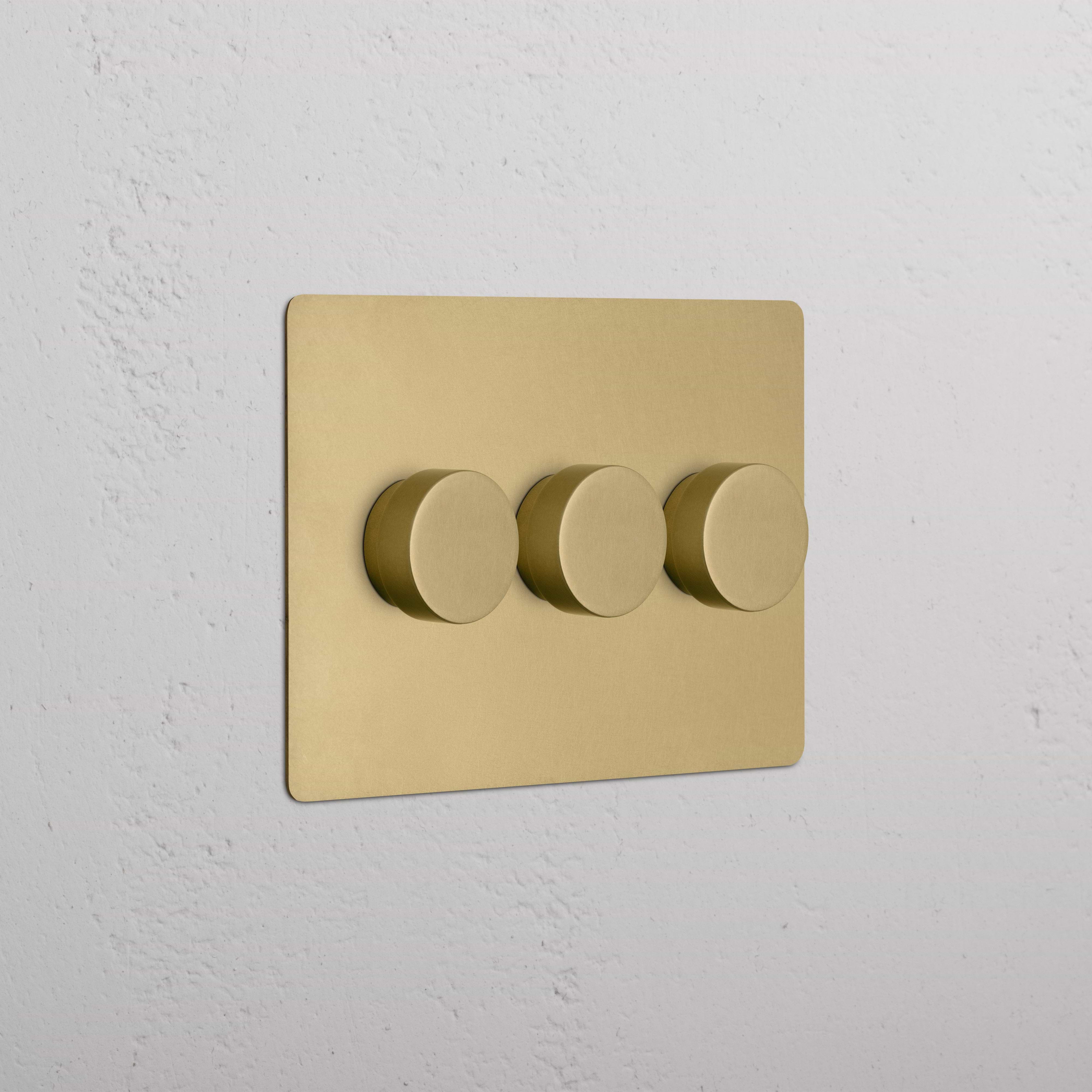 Kew 3G Dimmer Switch in antique brass with three round knobs on a brass wall plate.