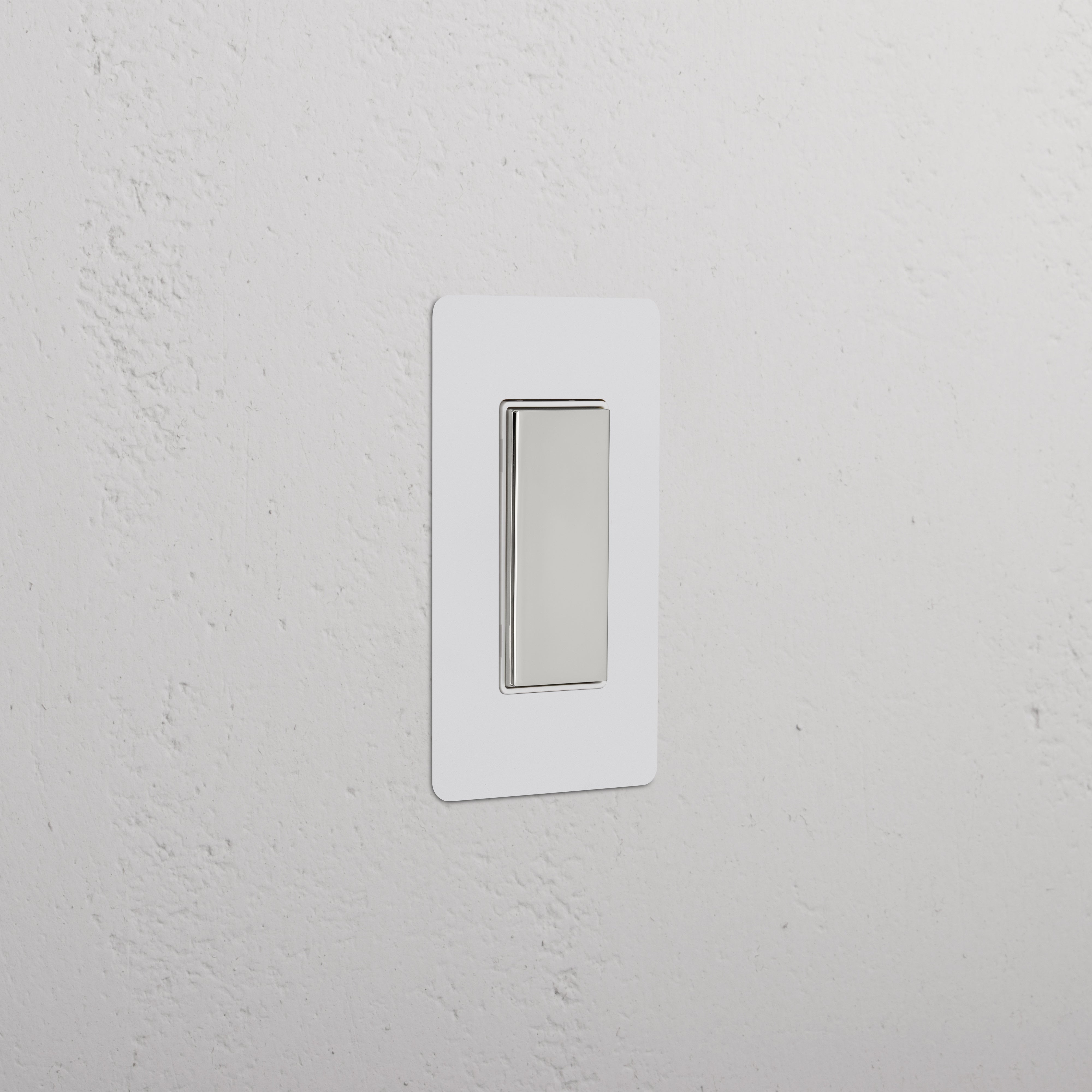 Kew 1G Center Retractive Rocker Switch in Paintable Polished Nickel White, mounted on a white wall.