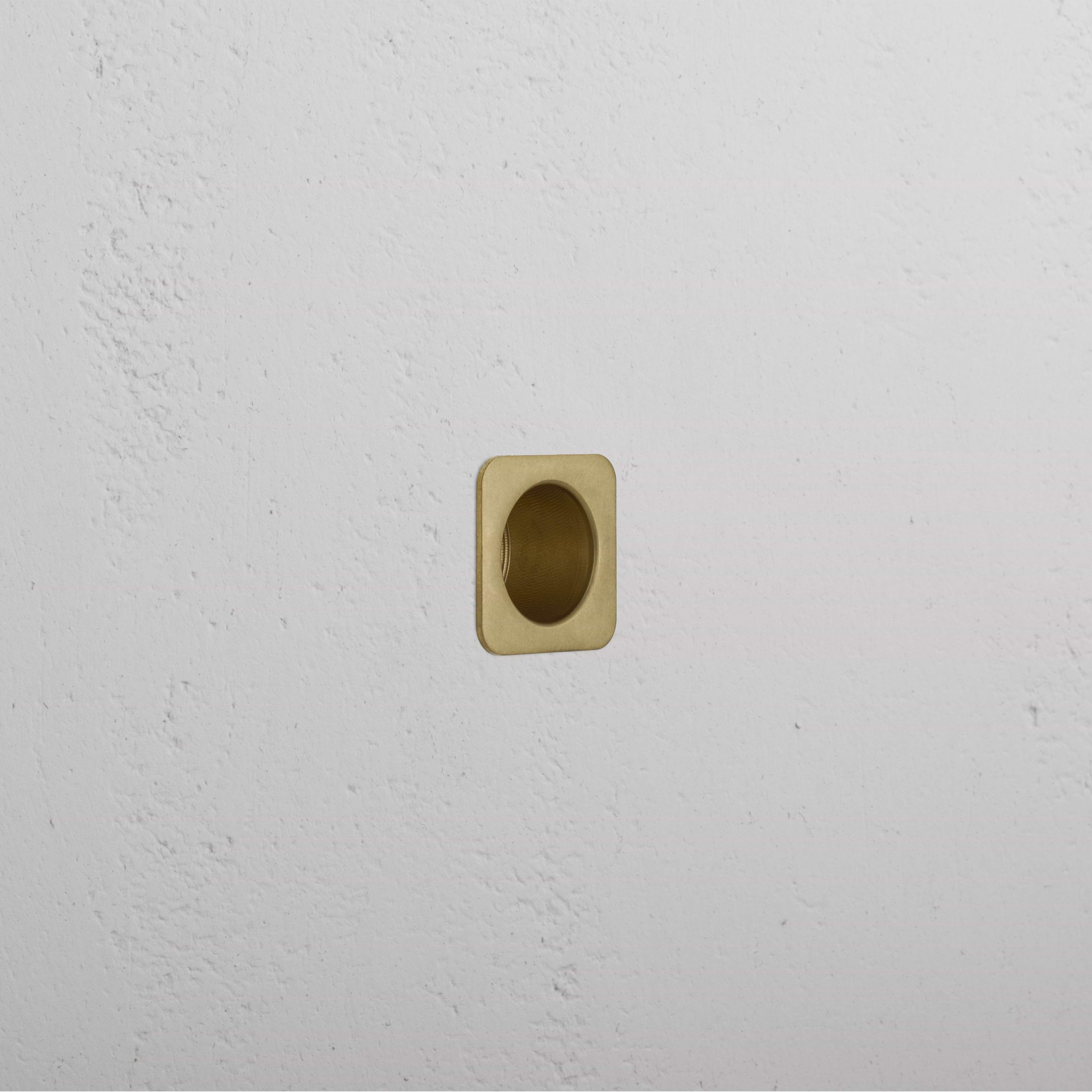 Regent Recessed Edge Pull in antique brass, square design, installed flush with a white textured wall.