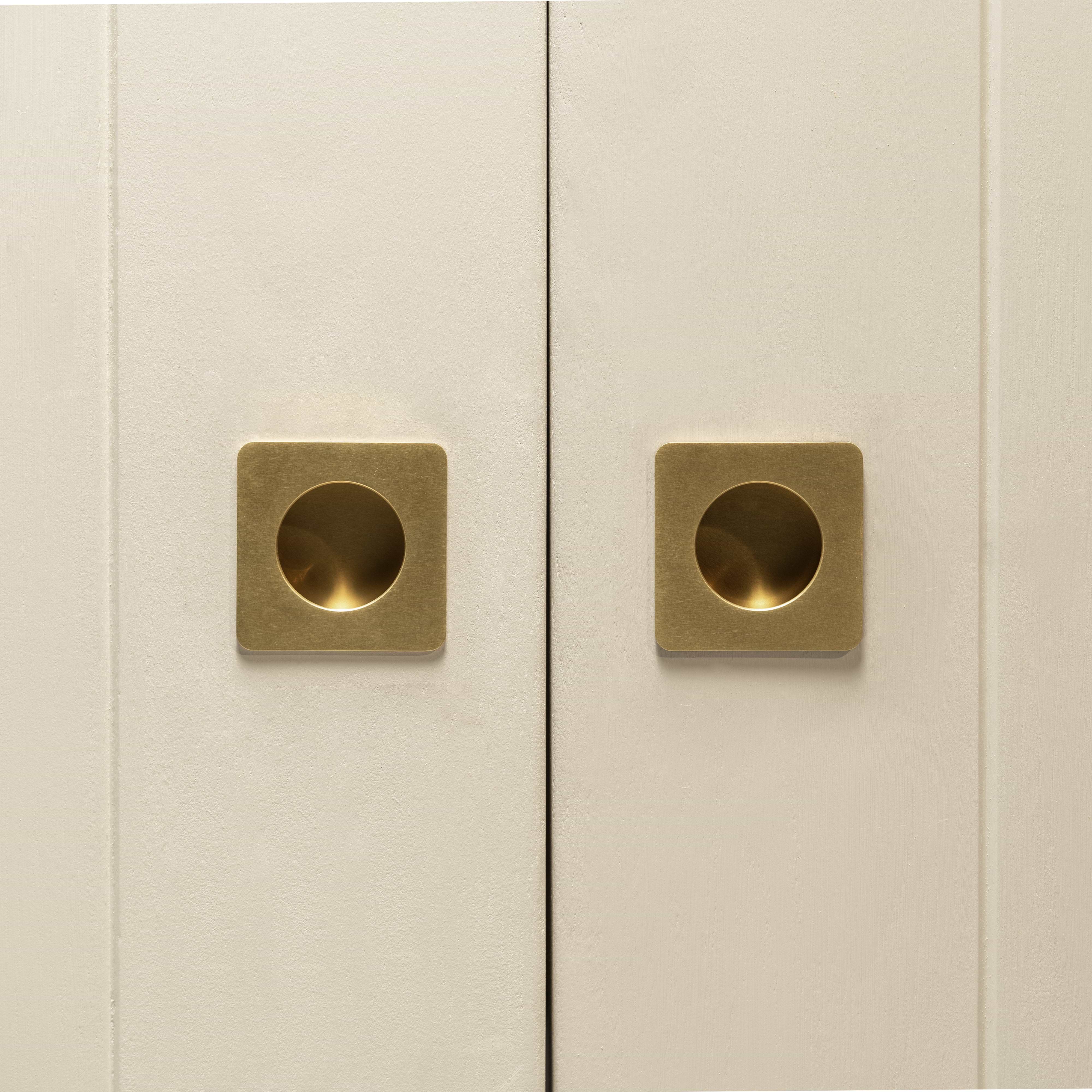 Close-up of two cabinet doors with Regent Recessed Small Pulls in Antique Brass, center-mounted and minimalistic.