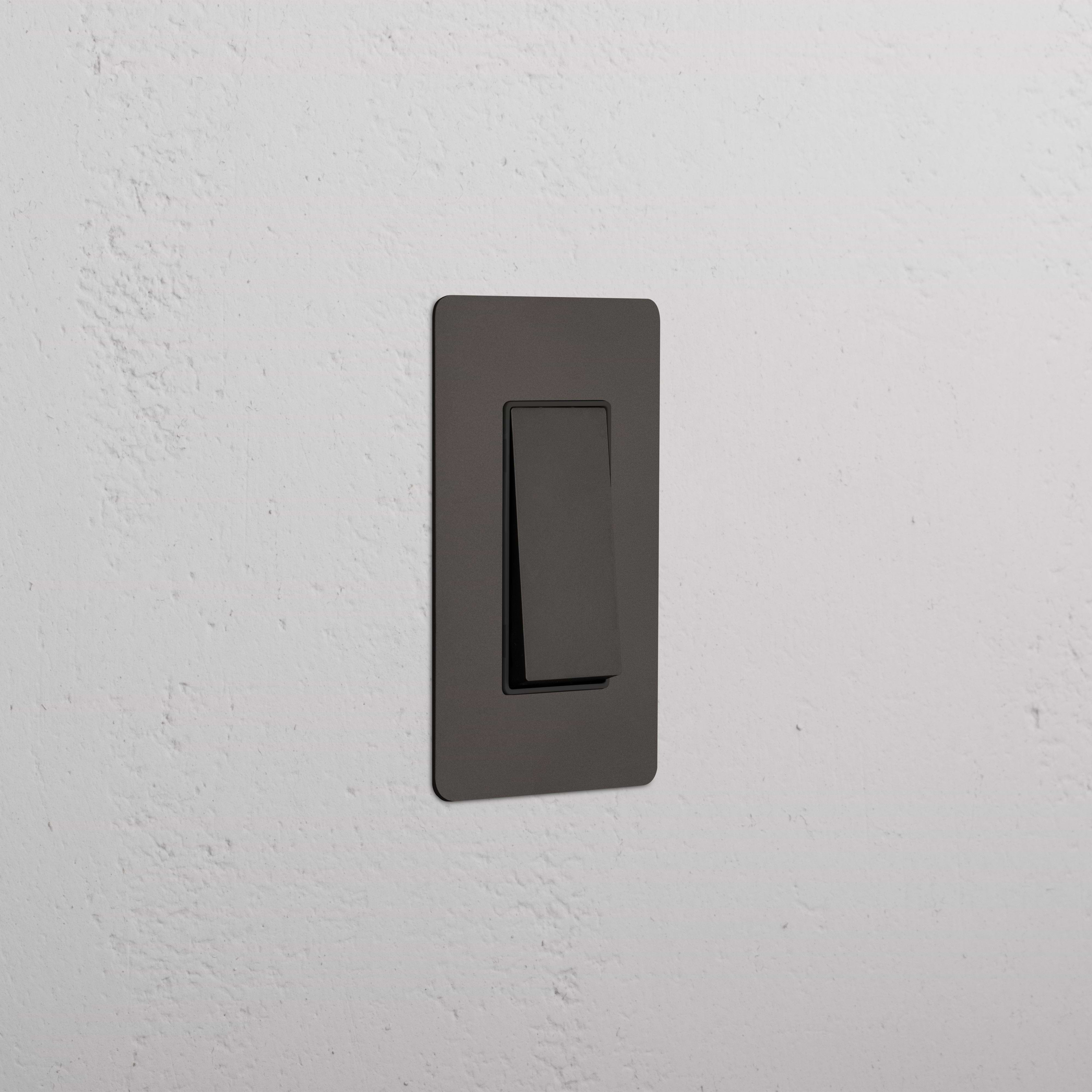 Kew 1G Retractive Rocker Switch in bronze black finish, single-gang, mounted on a wall.
