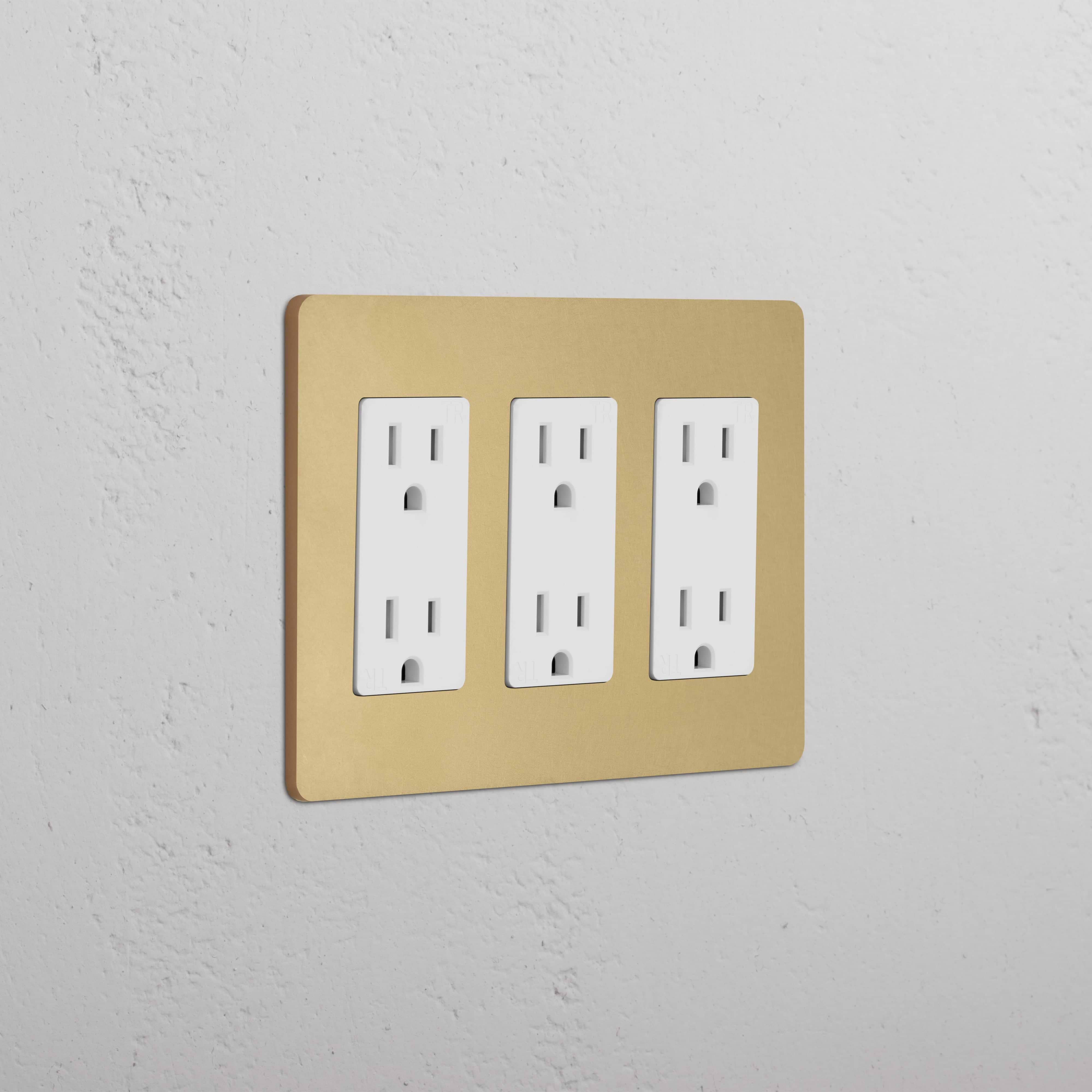 Grove 3G Outlet in antique brass with three white sockets, shown mounted on a white wall.