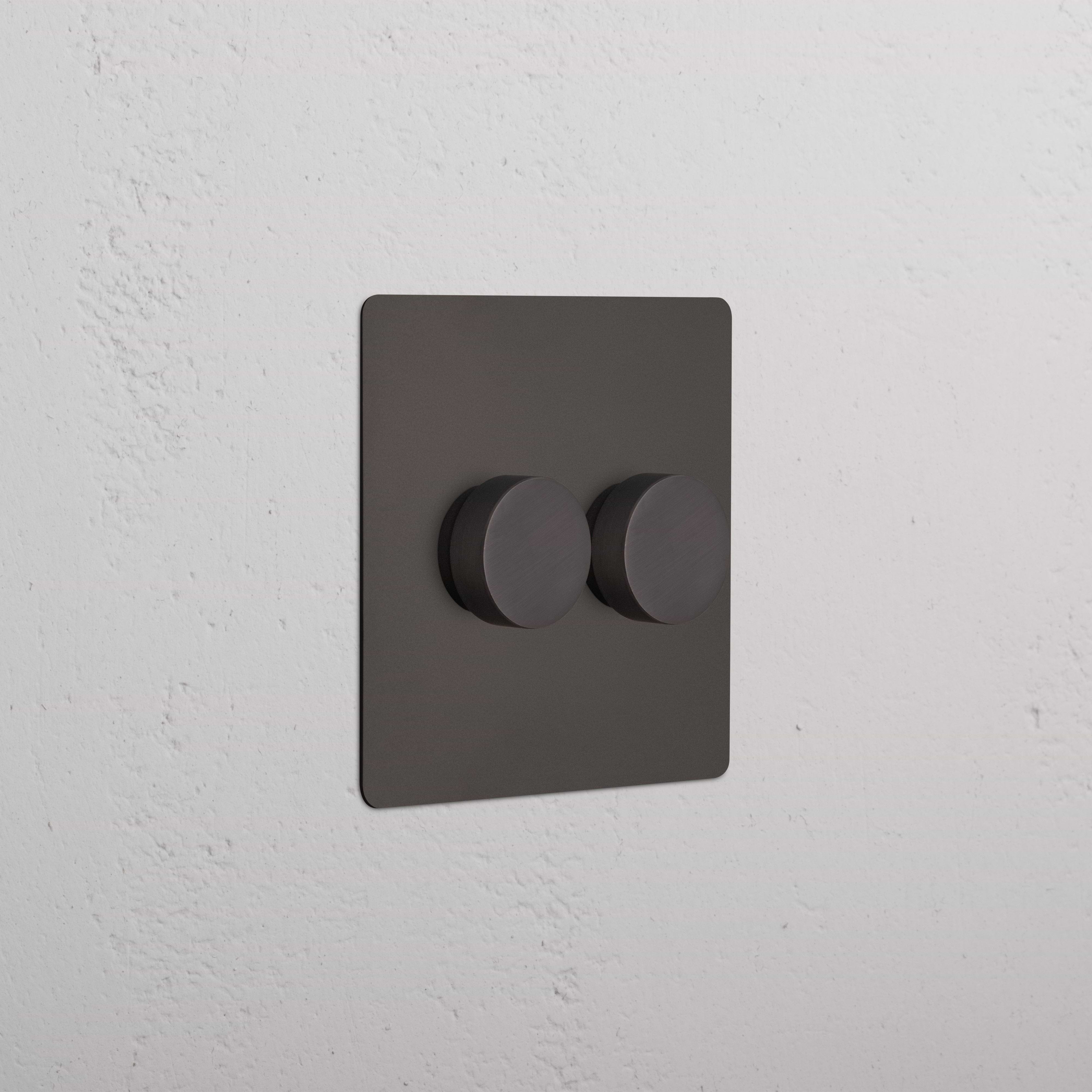 Bronze Kew 2G Dimmer Switch featuring two round knobs, installed on a white wall.
