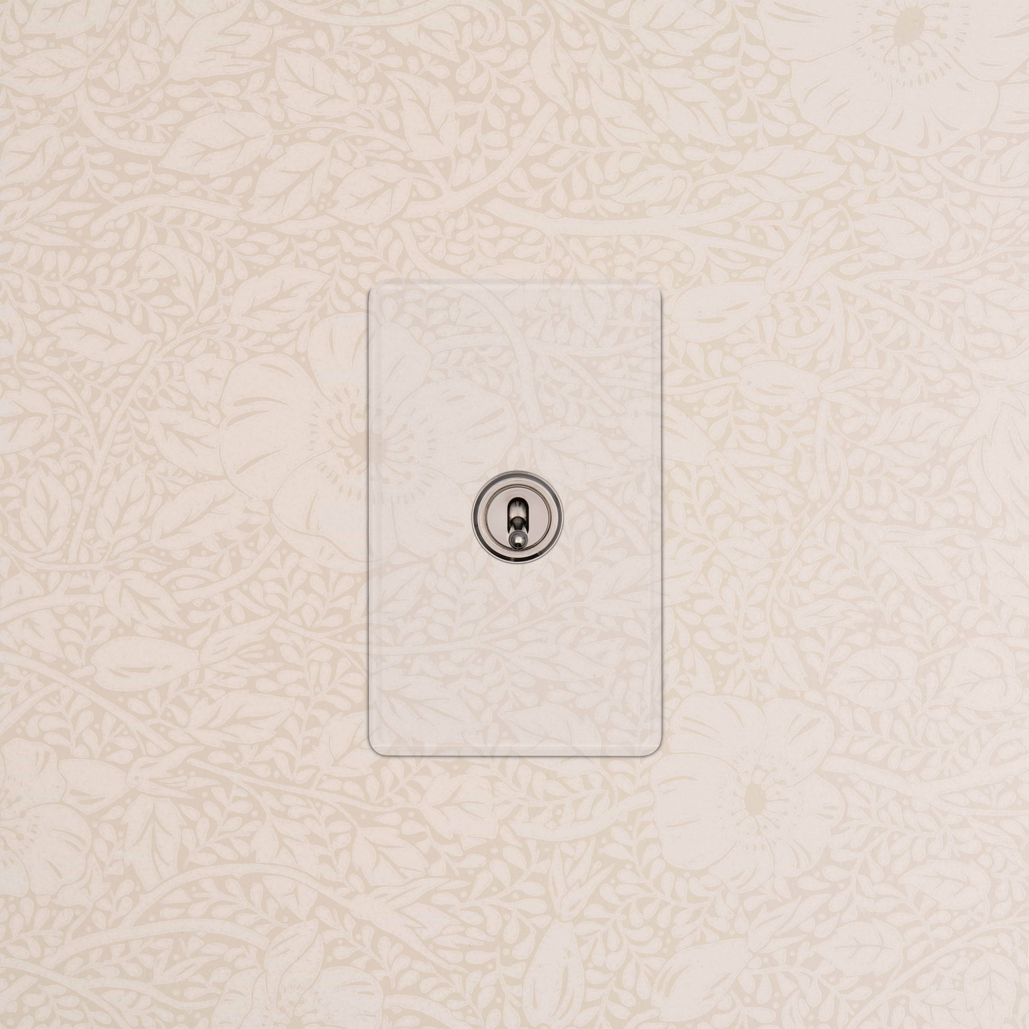 Kew 1G Retractive Toggle Switch in clear polished nickel, mounted on a beige floral-patterned wall.
