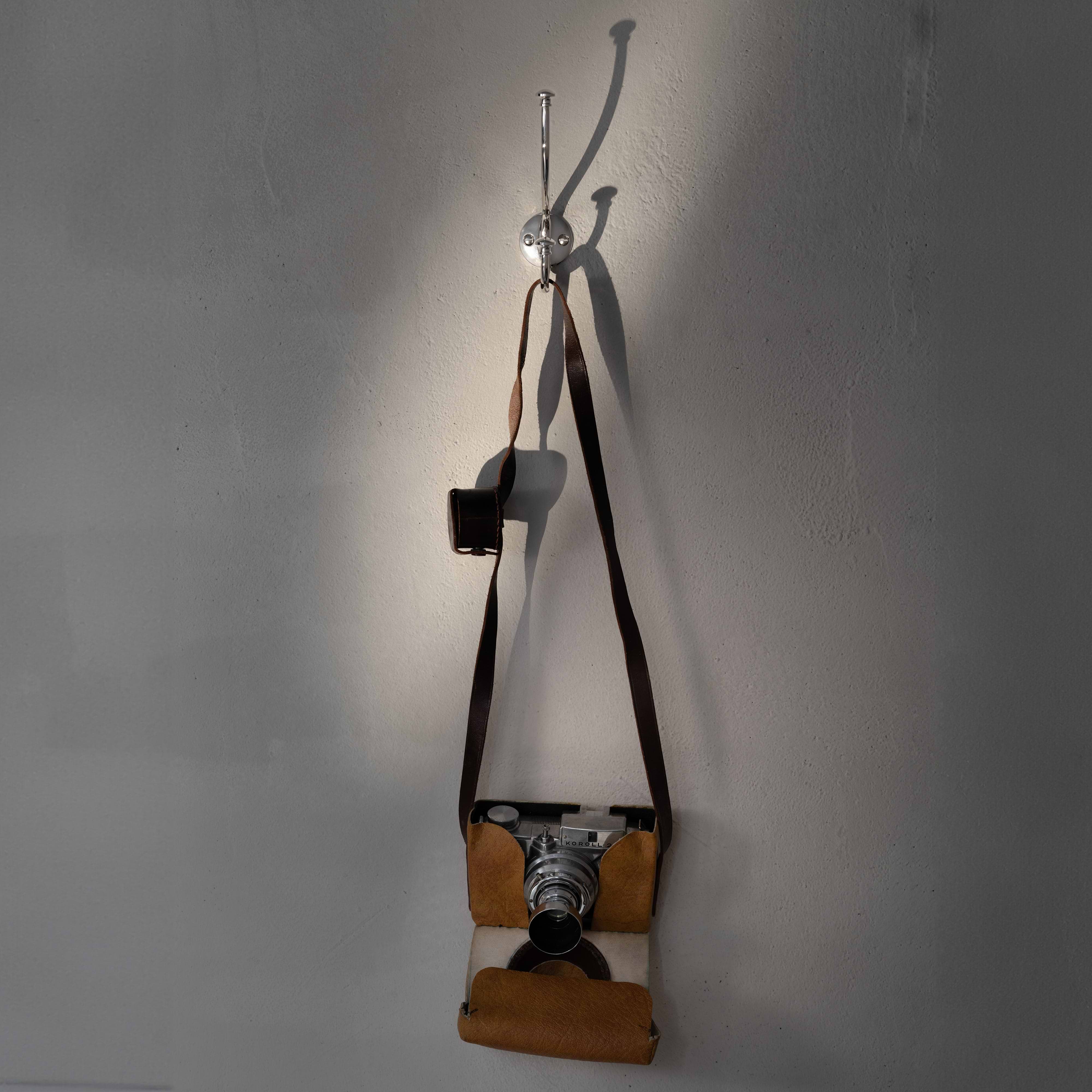 Polished Nickel Mews Hook mounted on a light gray wall, designed for hanging items.