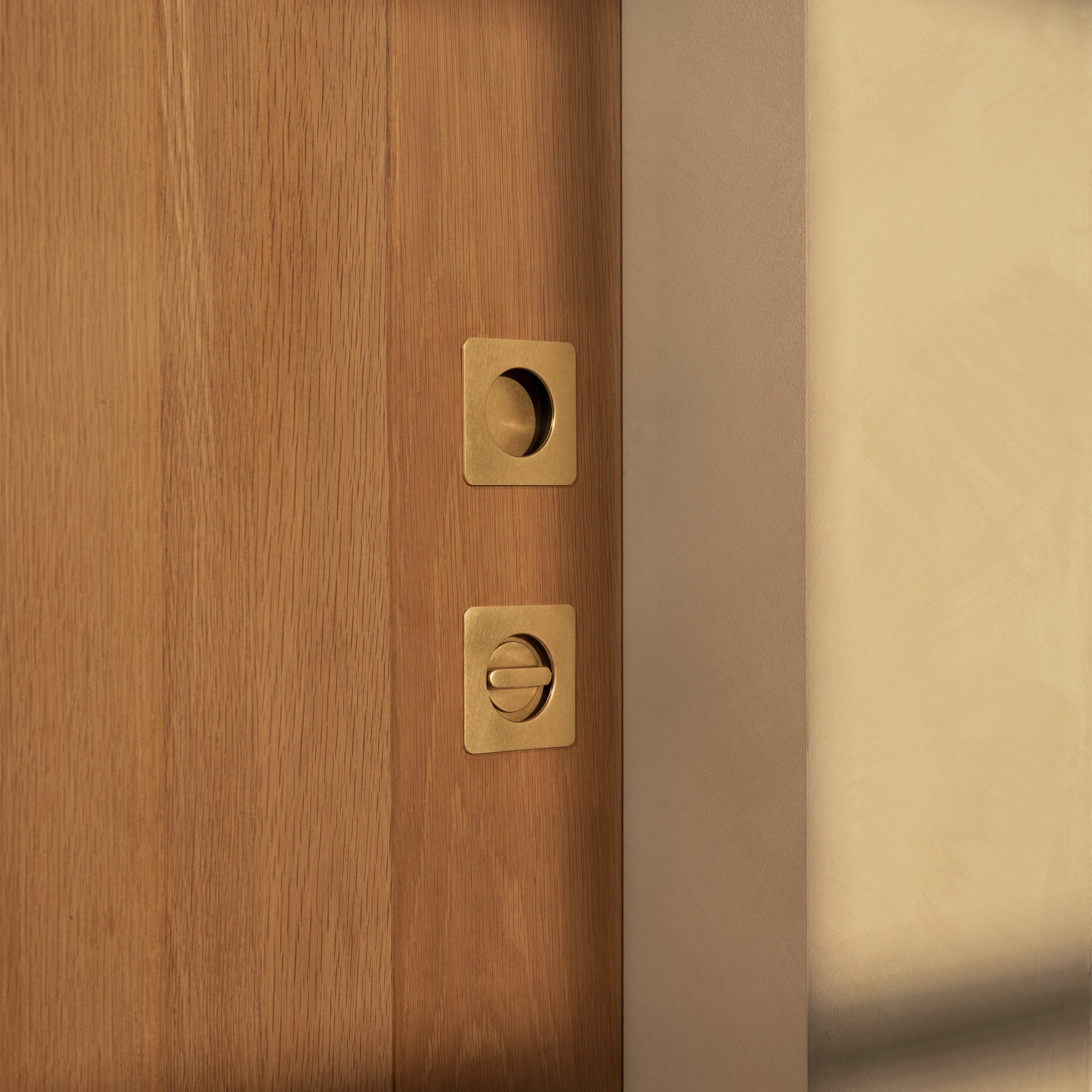 Regent Recessed Thumbturn in antique brass finish, installed on a door, with round recessed design.