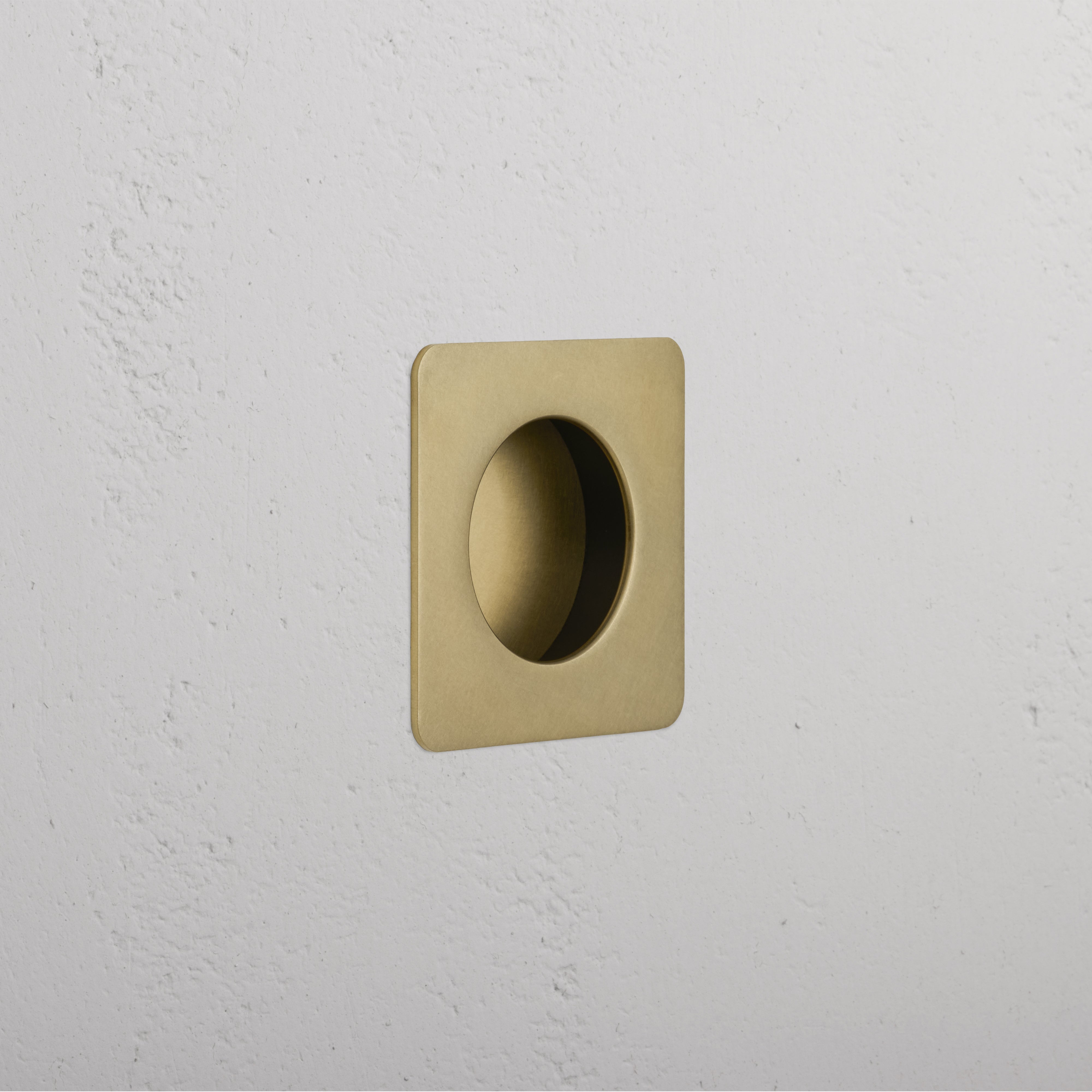 Regent Recessed Small Pull in antique brass, square shape with circular indent, mounted on white wall.