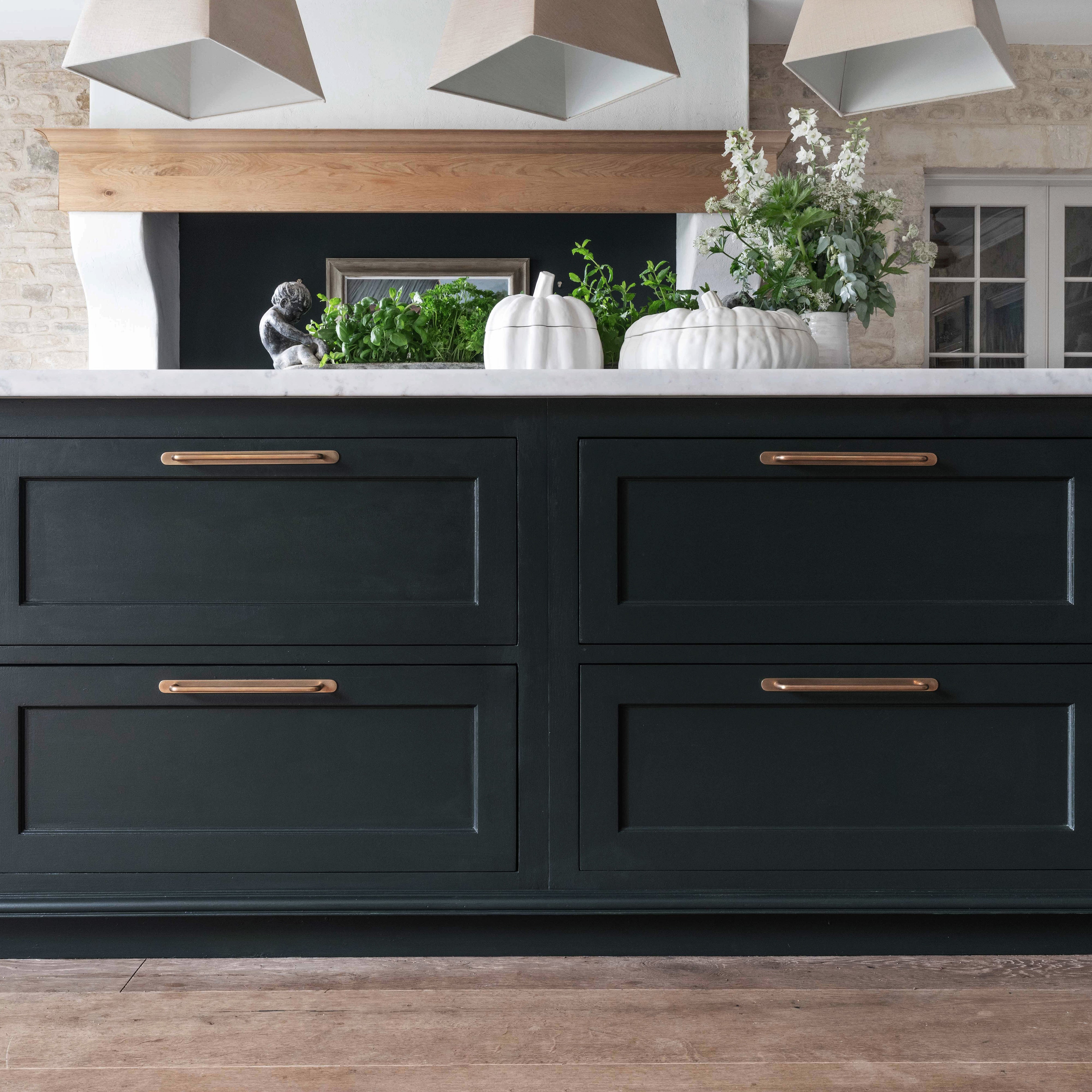 Close-up of Kilburn Furniture Handle Large in Antique Brass mounted on a dark green cabinet drawer.