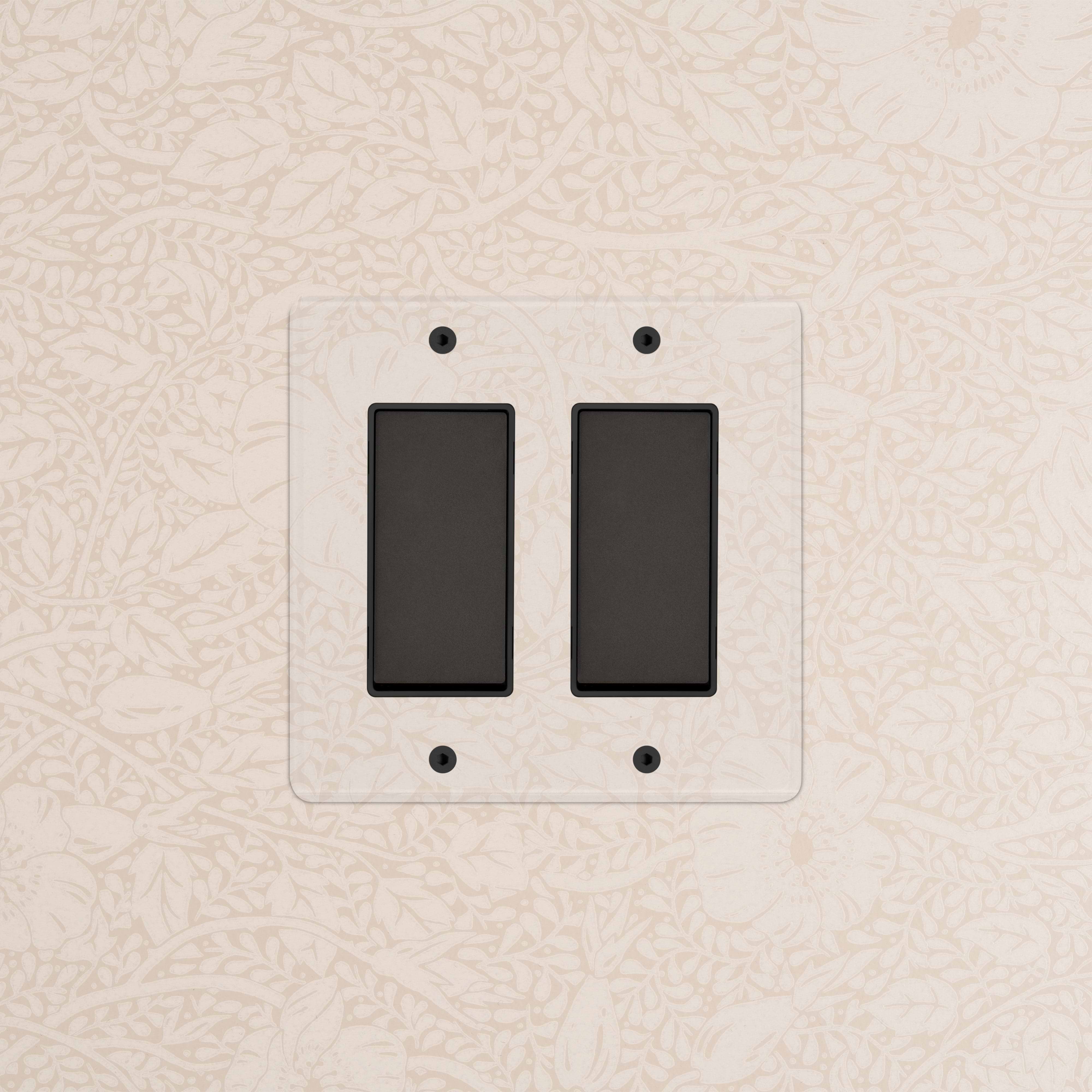 Kew 2G Rocker Switch with black switches and a clear bronze black plate mounted on floral wallpapered wall.