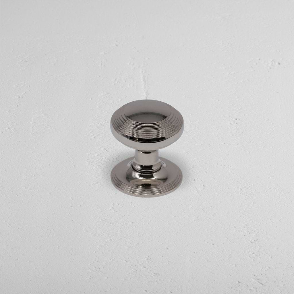 Polished nickel Poplar Dummy Door Knob Set with round shape and subtle grooves on a white surface.