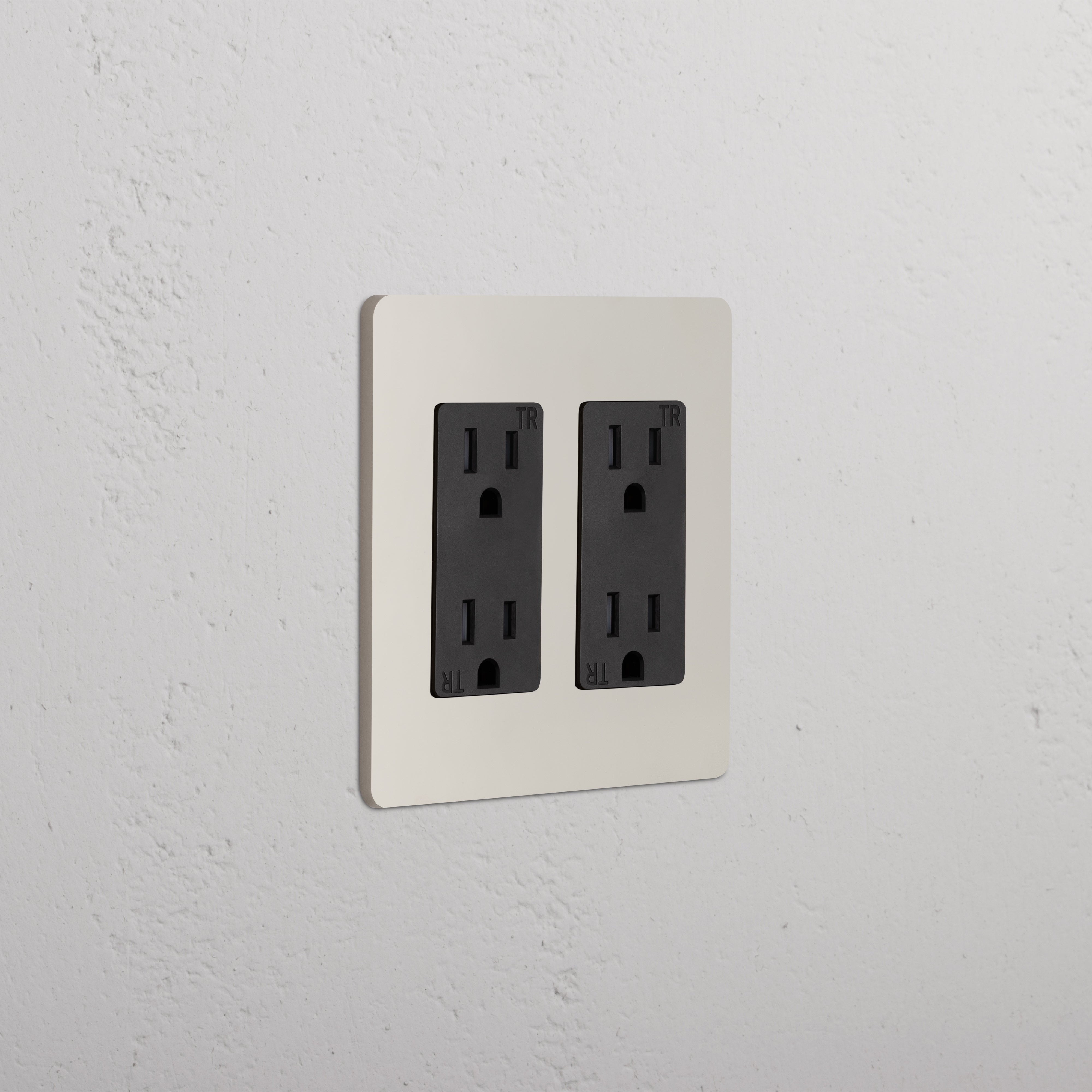 Grove 2G Outlet in polished nickel black finish with two black double sockets on a lightly textured wall.