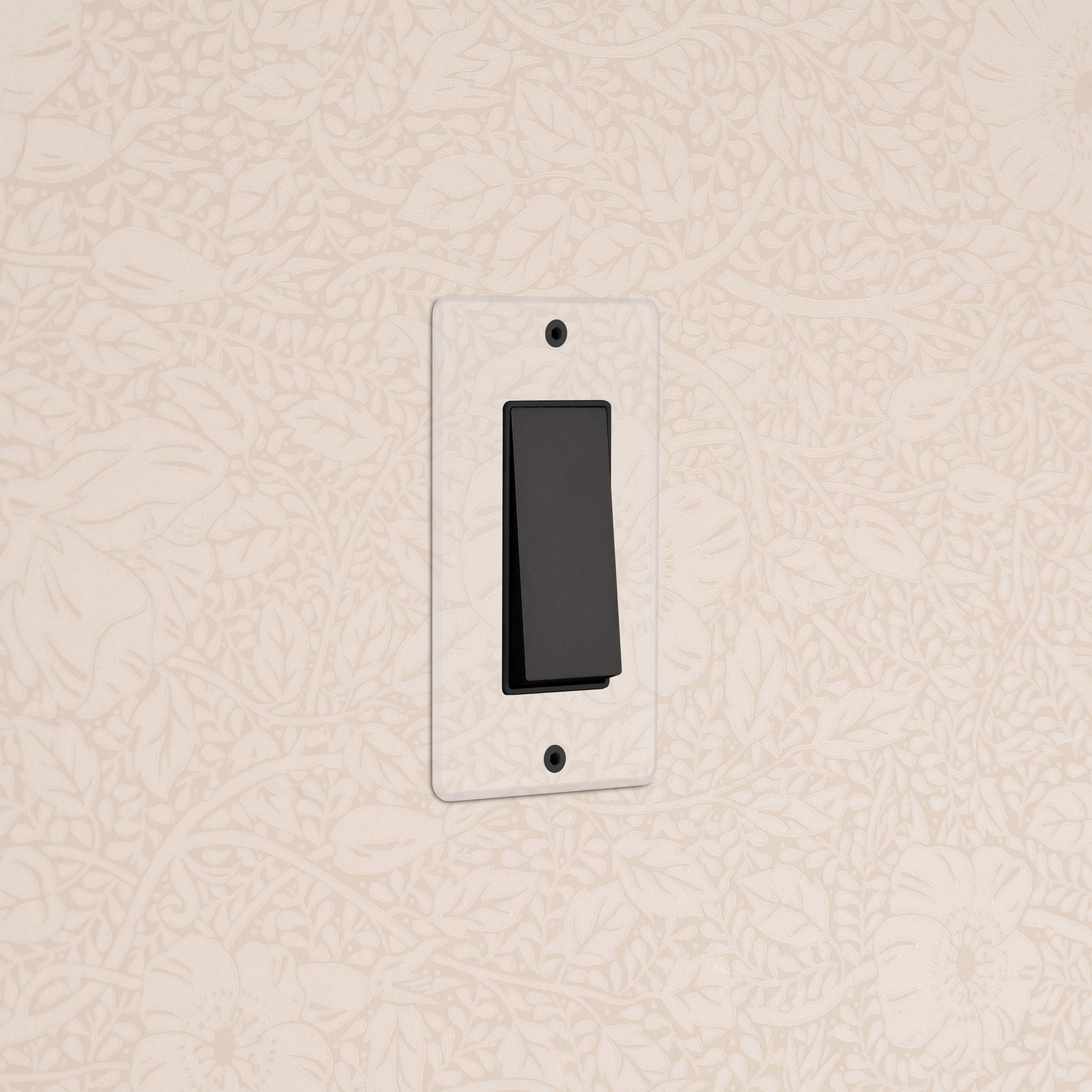 Kew 1G Retractive Rocker Switch in Clear Bronze Black mounted on beige floral wallpapered wall.