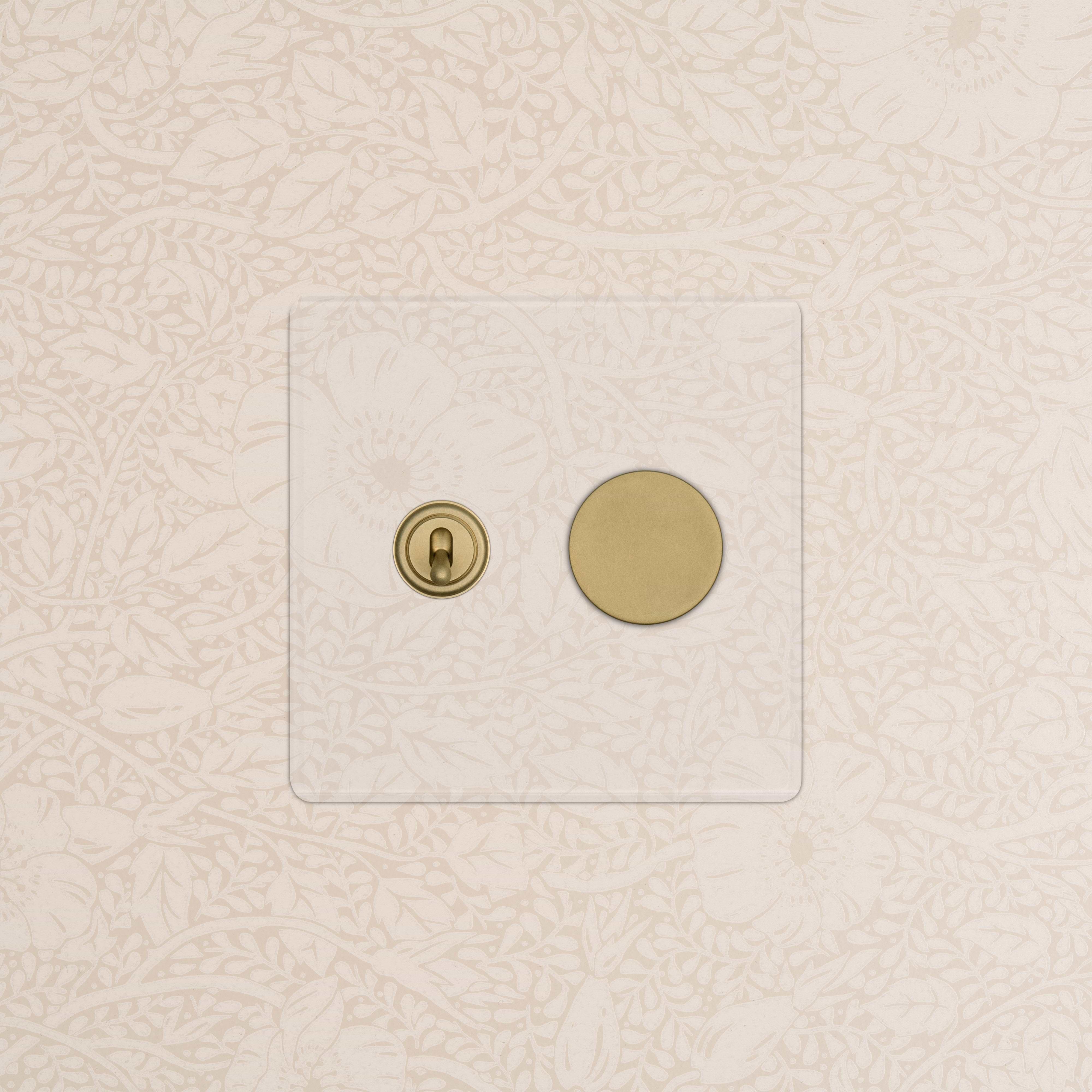 Kew 2G Toggle & Dimmer Switch in Clear Antique Brass finish, shown on floral beige wallpaper.