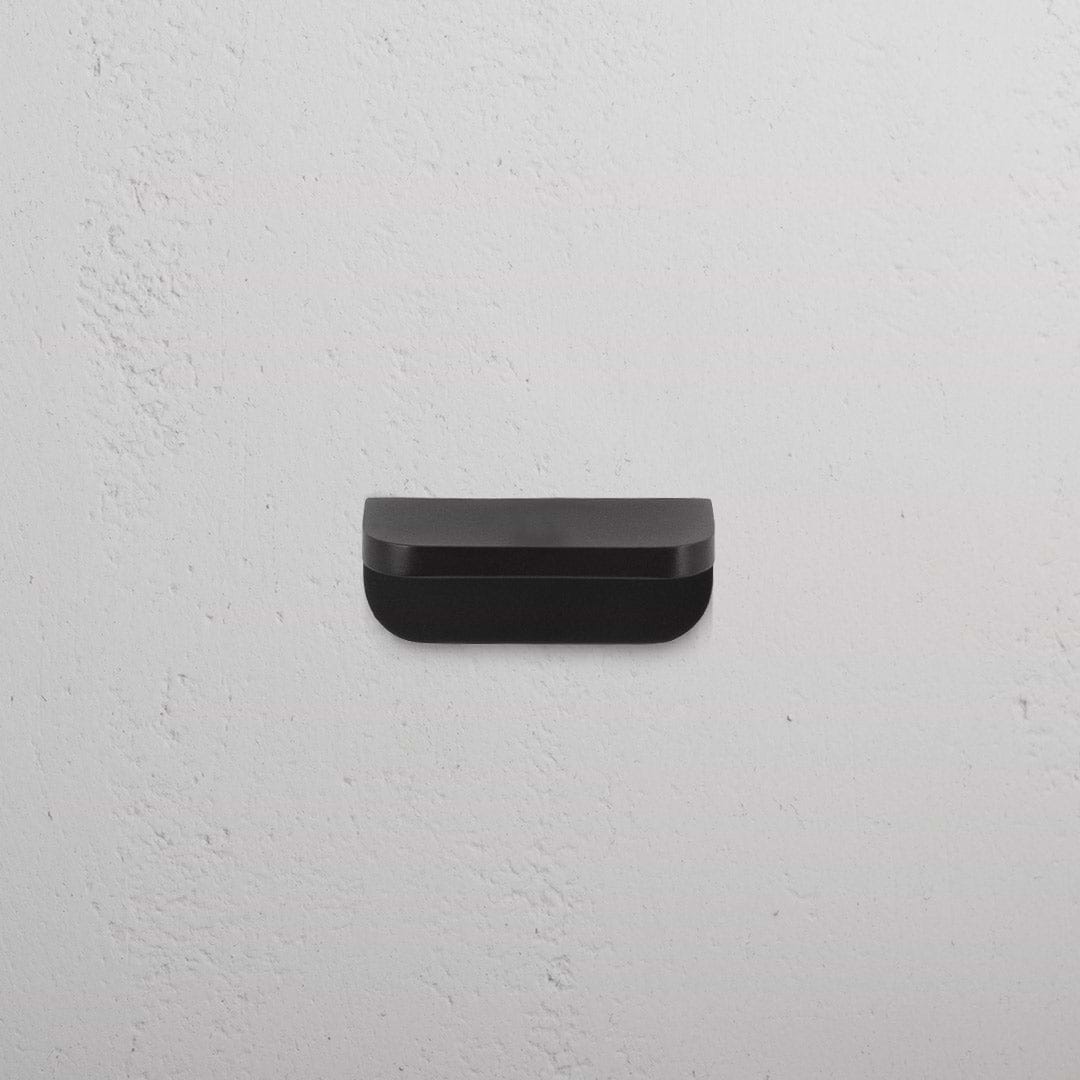 Bronze Oxford Furniture Handle Extra Small, rectangular with rounded edges, mounted on a white wall.
