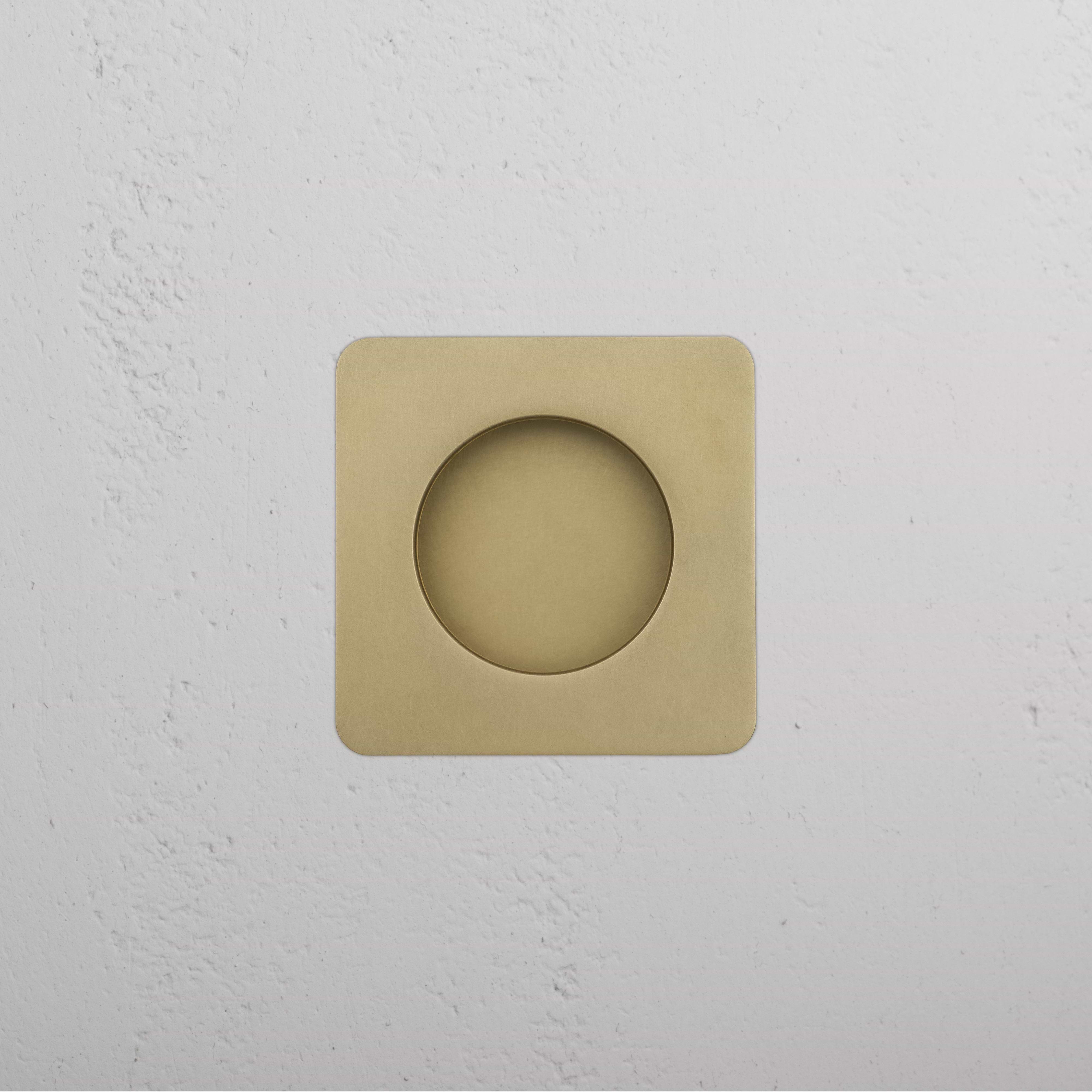 Regent Recessed Small Pull in Antique Brass, square design with center cutout, mounted on white wall.