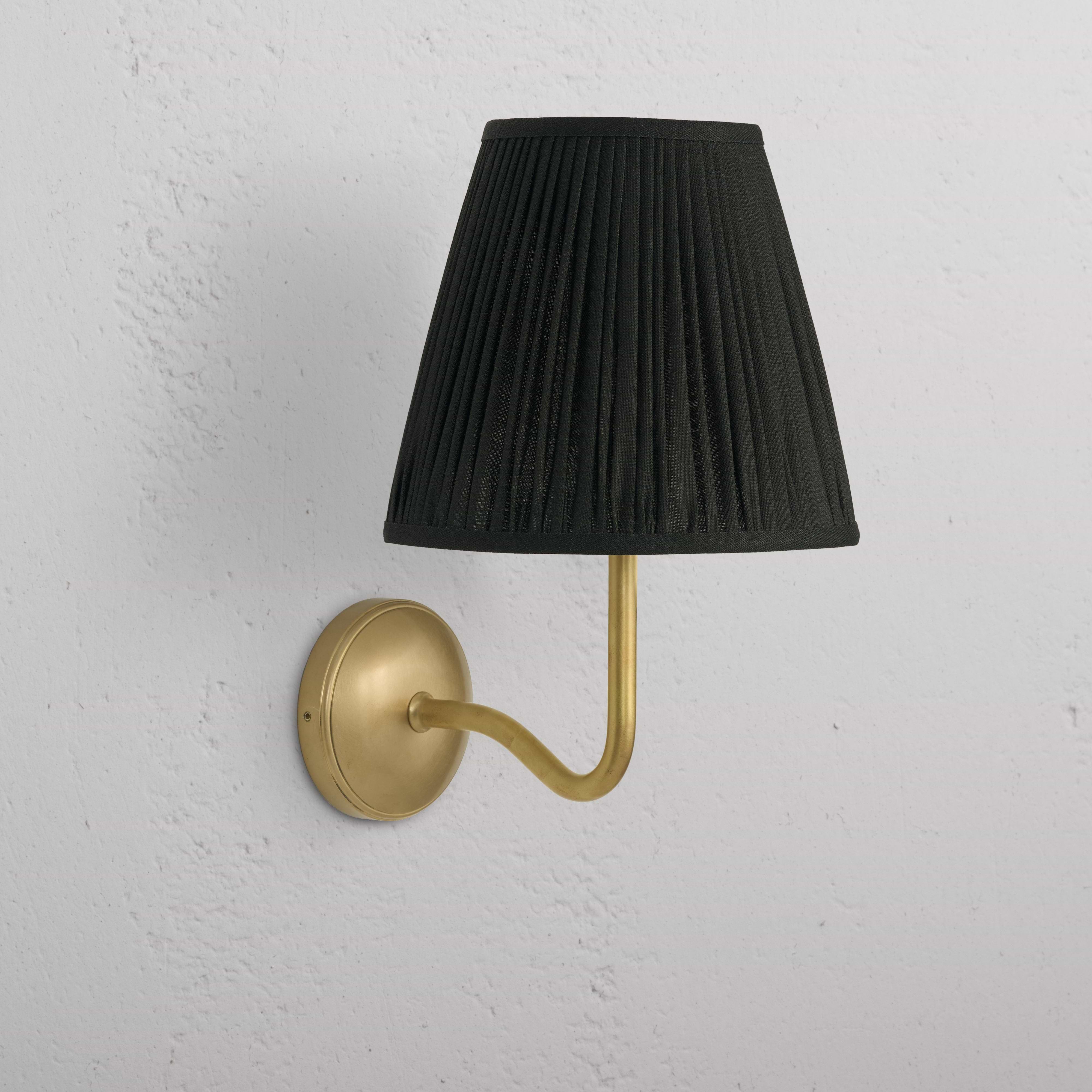 Large Malvern Wall Light in deep green with antique brass curved arm and round base, mounted on a white wall.