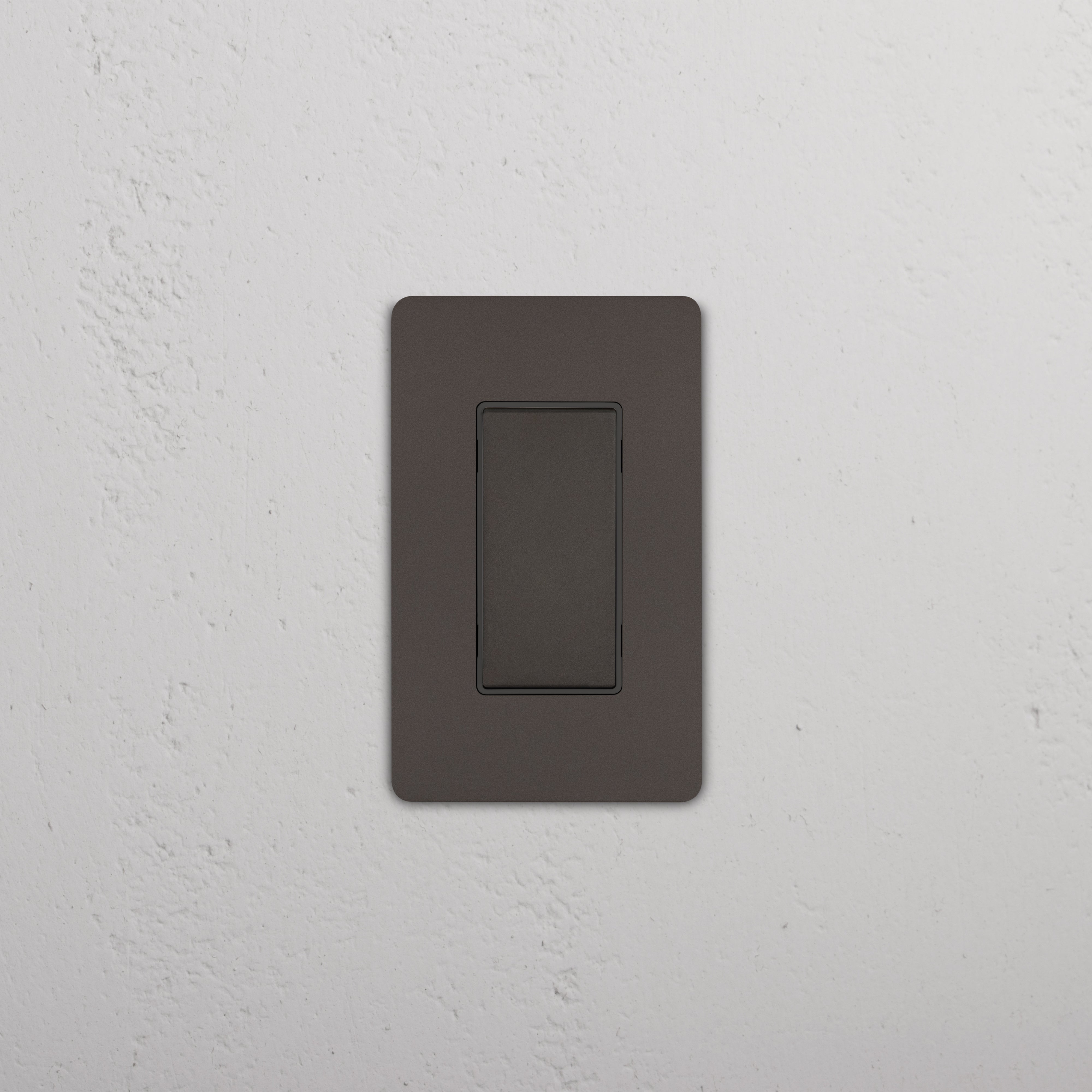Grove 1G Center Retractive Rocker Switch in Bronze Black finish, shown mounted on a white wall.