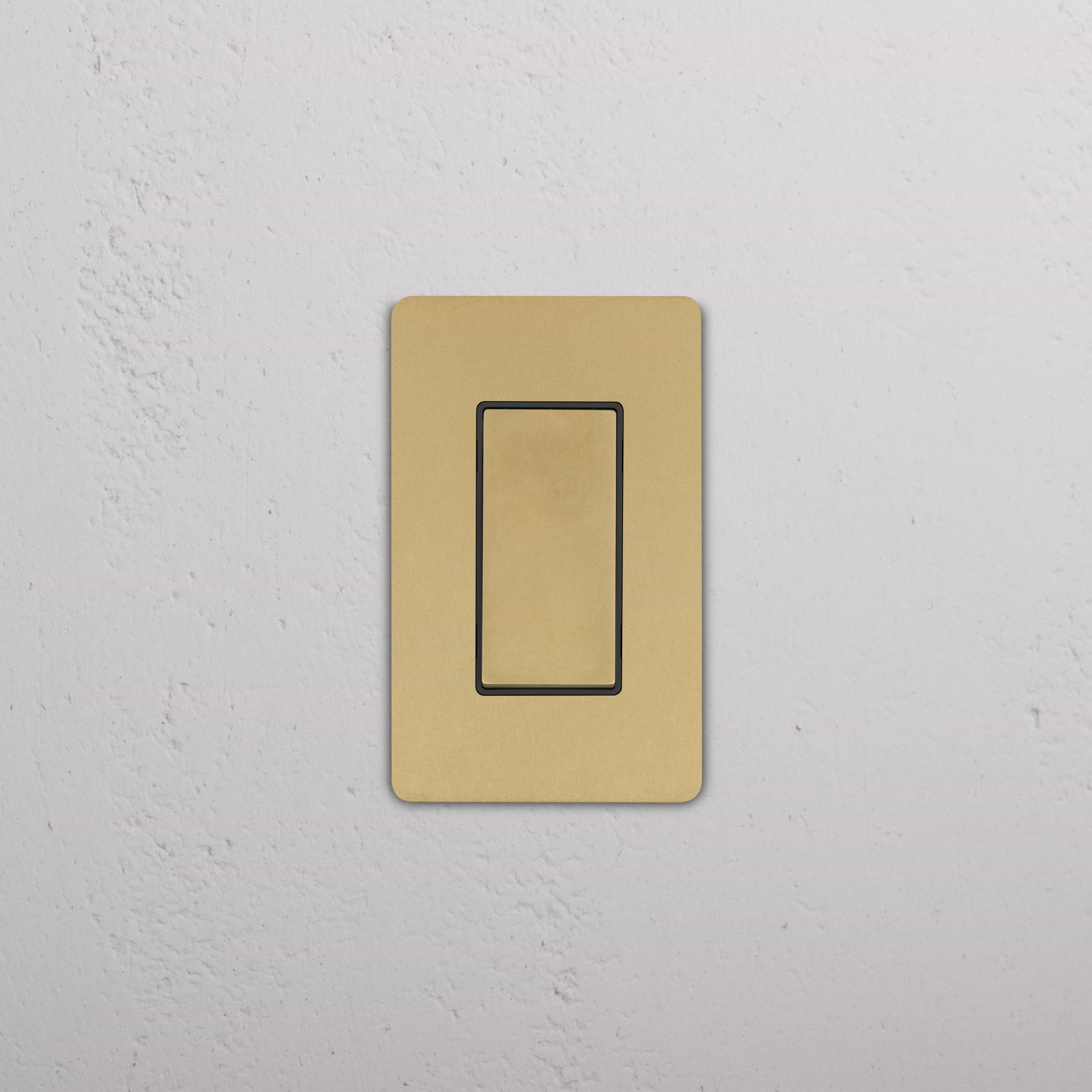 Grove 1G Rocker Switch in antique brass black finish on a rectangular plate, mounted on a white wall.