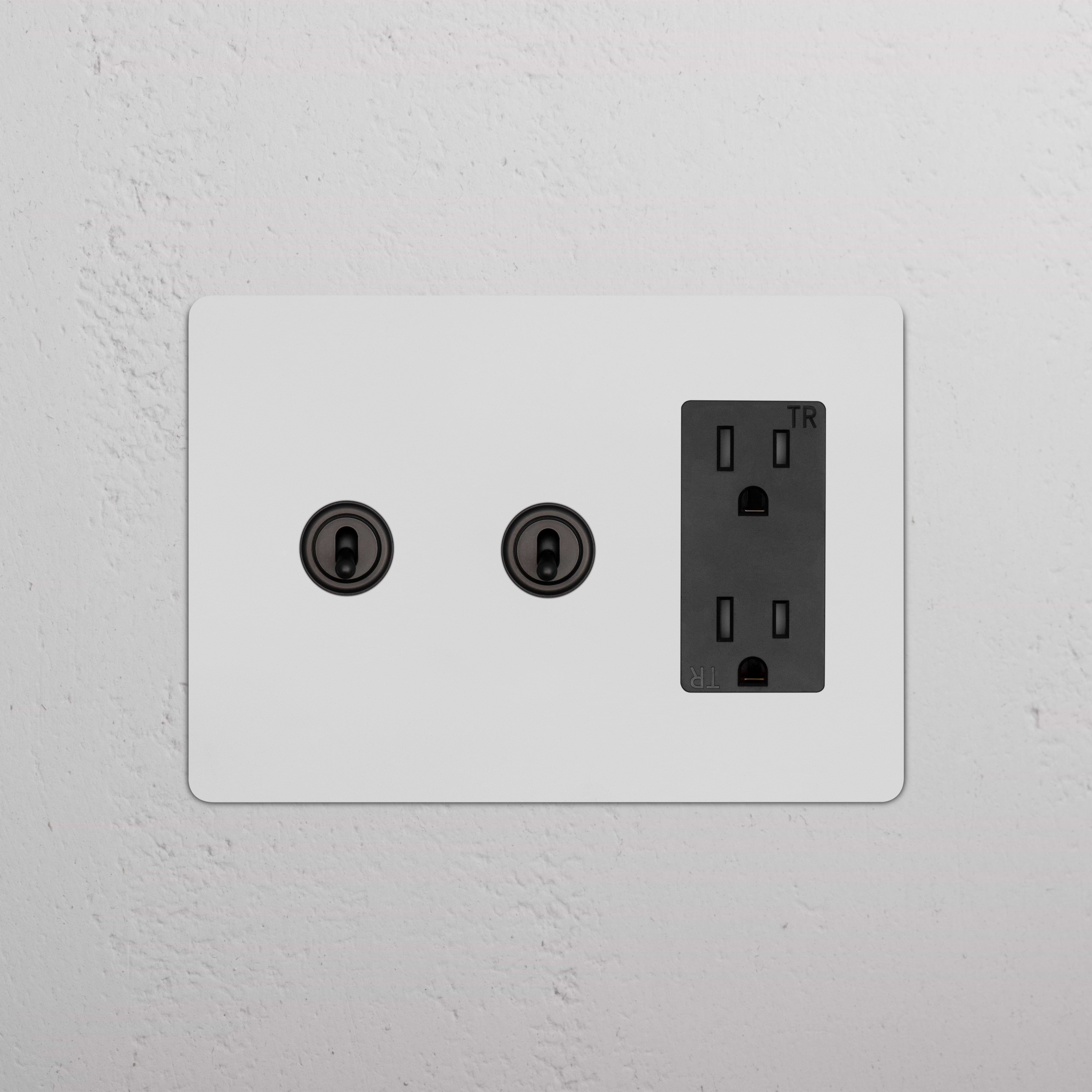 Kew 3G 2x Toggle Switch & Outlet in paintable bronze black finish, mounted on a light wall.