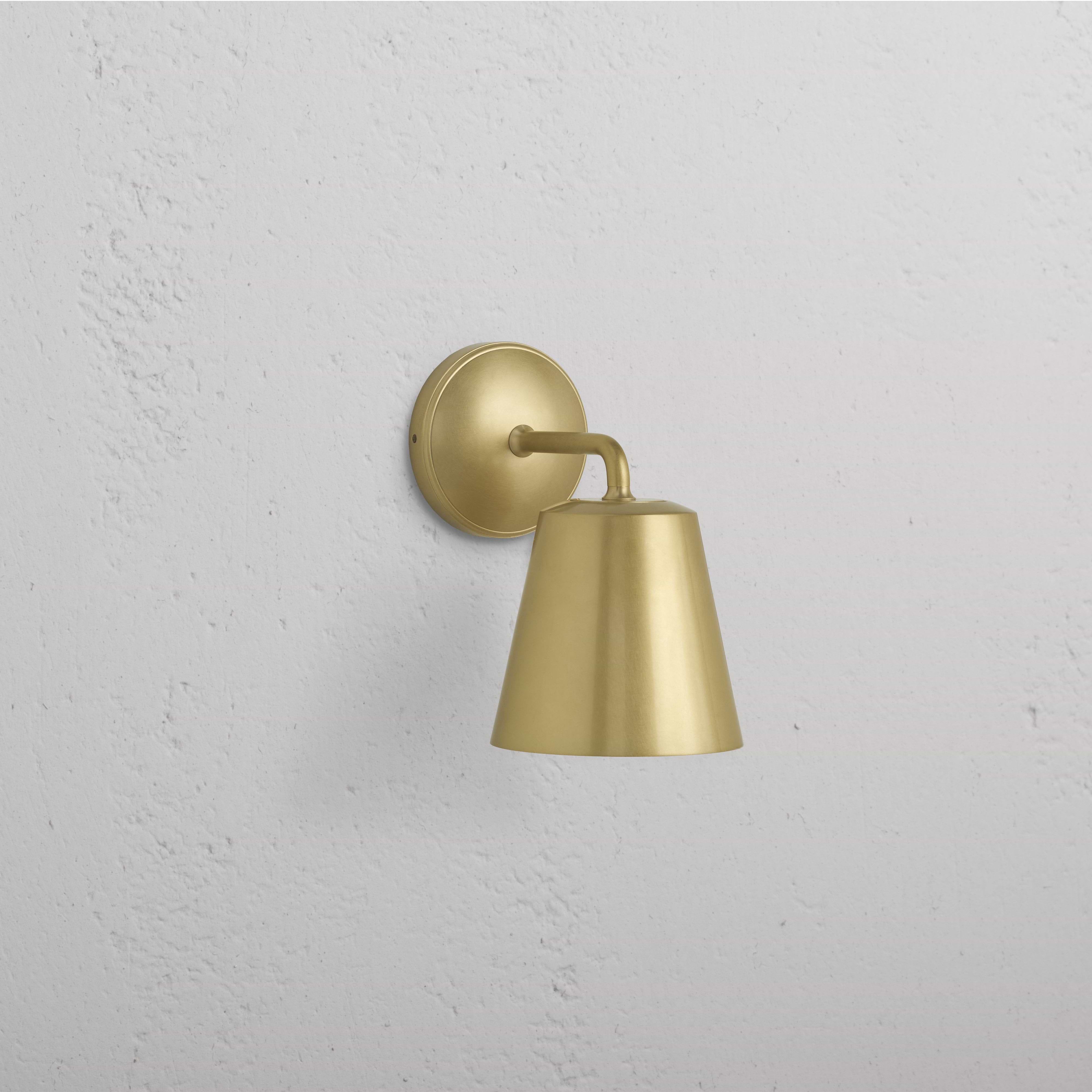 Richmond Medium Wall Light in Antique Brass with round base and conical shade, mounted on a white wall.