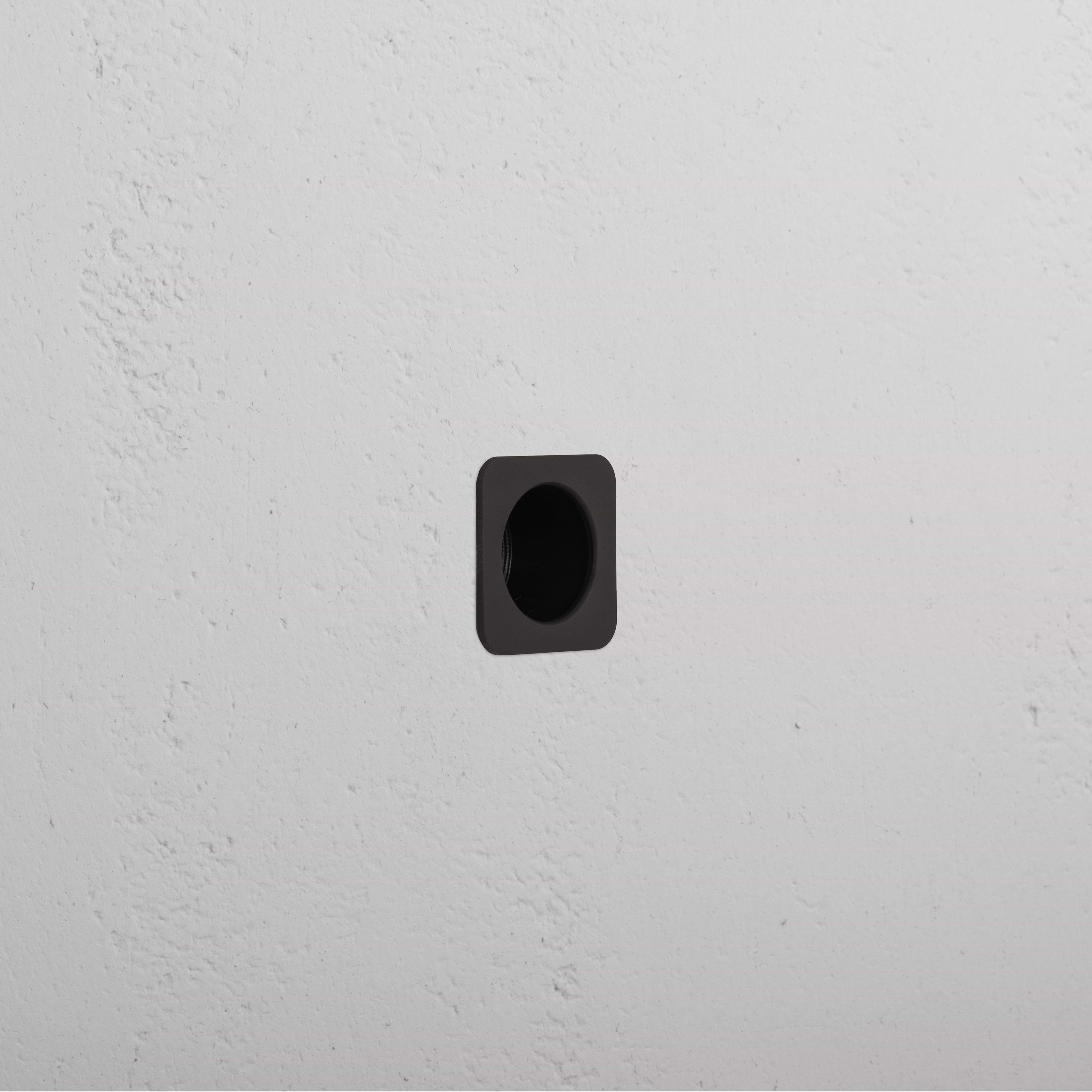 Regent Recessed Edge Pull in bronze, square design, installed flush in a white textured wall.