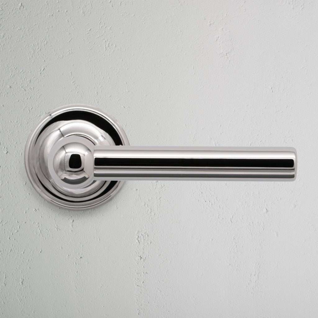 Harper Dummy Door Handle Set in polished nickel with a sleek cylindrical design, shown on a white wall.
