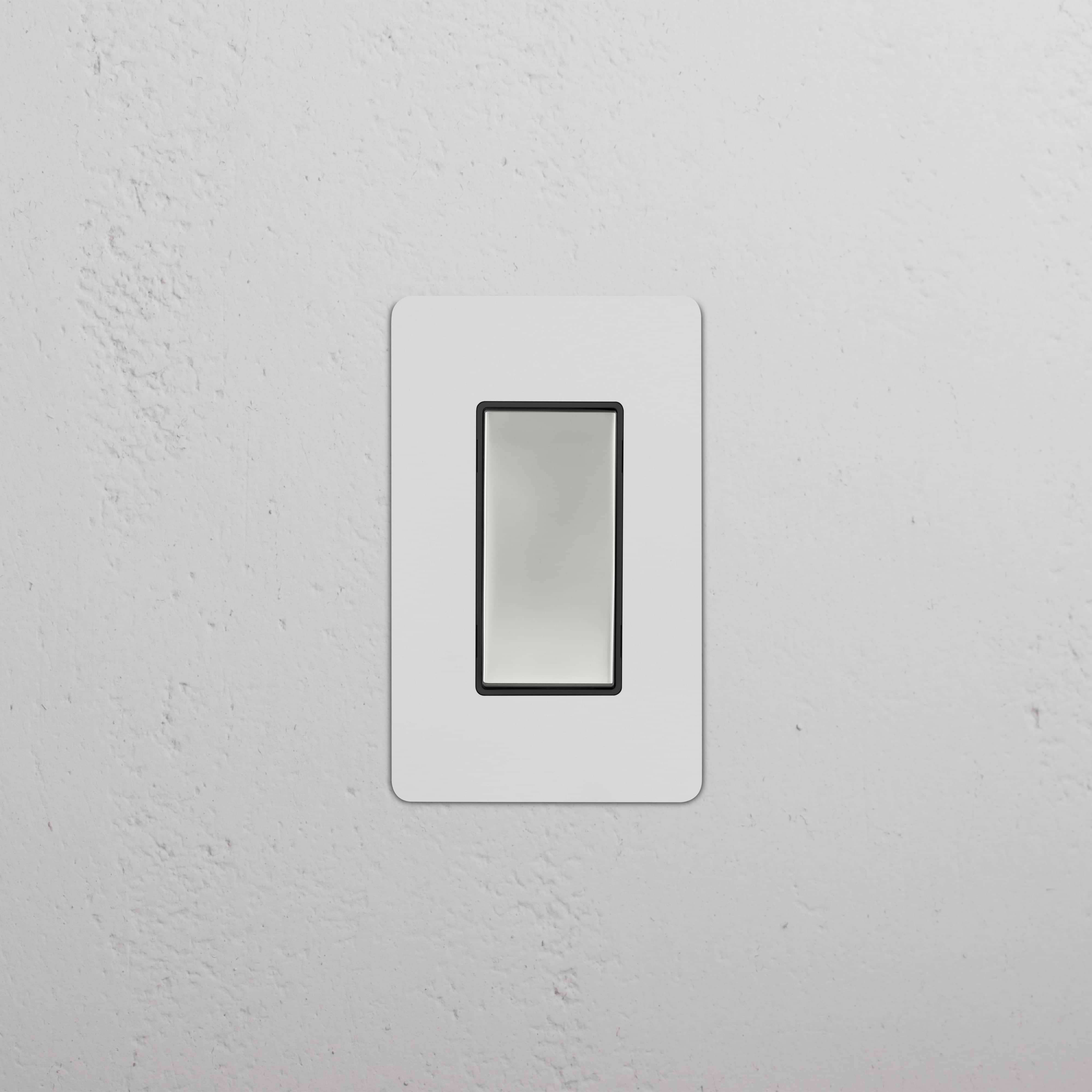 Kew 1G Retractive Rocker Switch in paintable polished nickel black, shown mounted on a white wall.