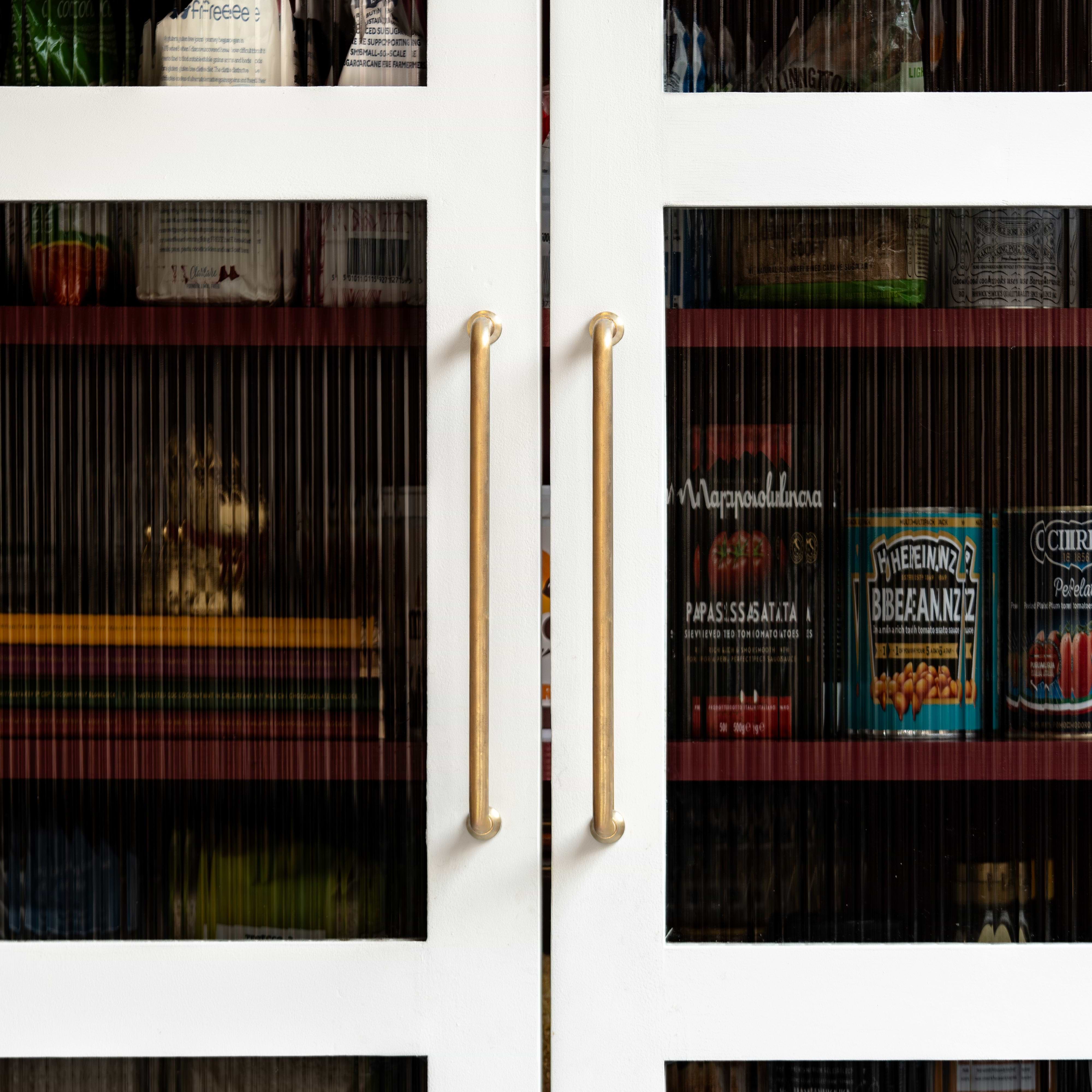 Sycamore Furniture Handle Medium in antique brass, mounted on a door, showing its classic design and finish.