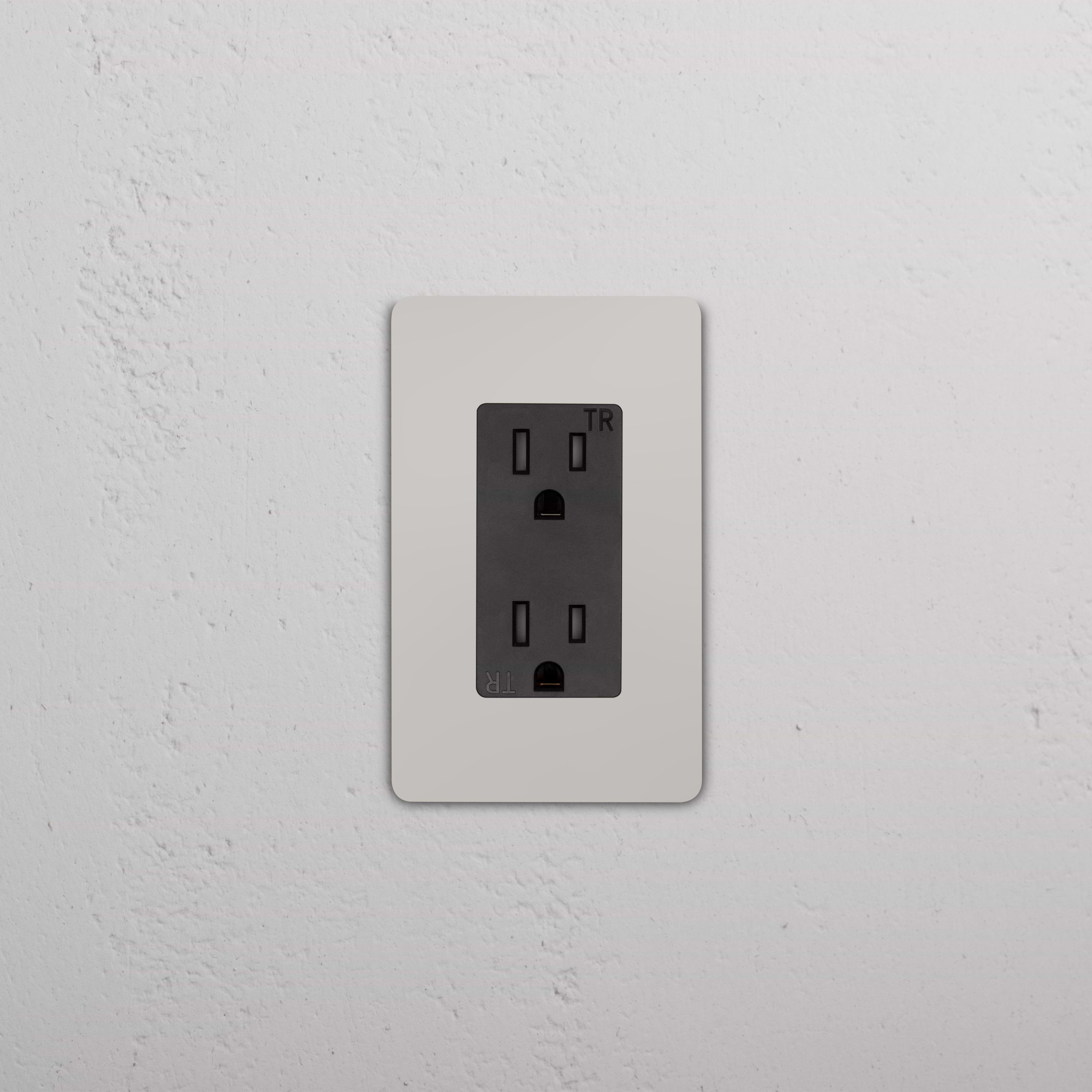 Grove 1G 15A Outlet in polished nickel black finish, installed on a textured white wall.