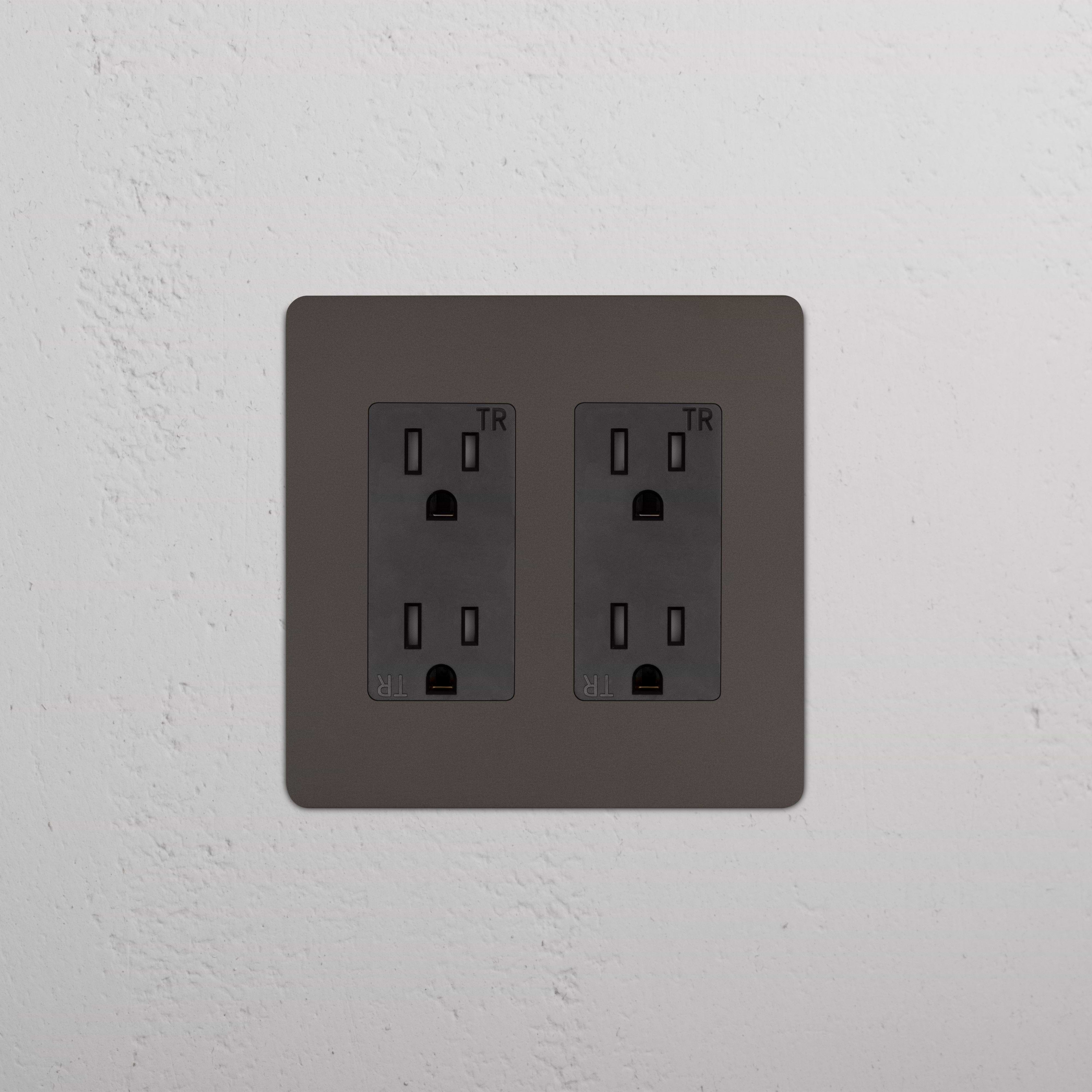 Kew 2G Outlet in Bronze Black with two three-prong sockets, installed on a white textured wall.