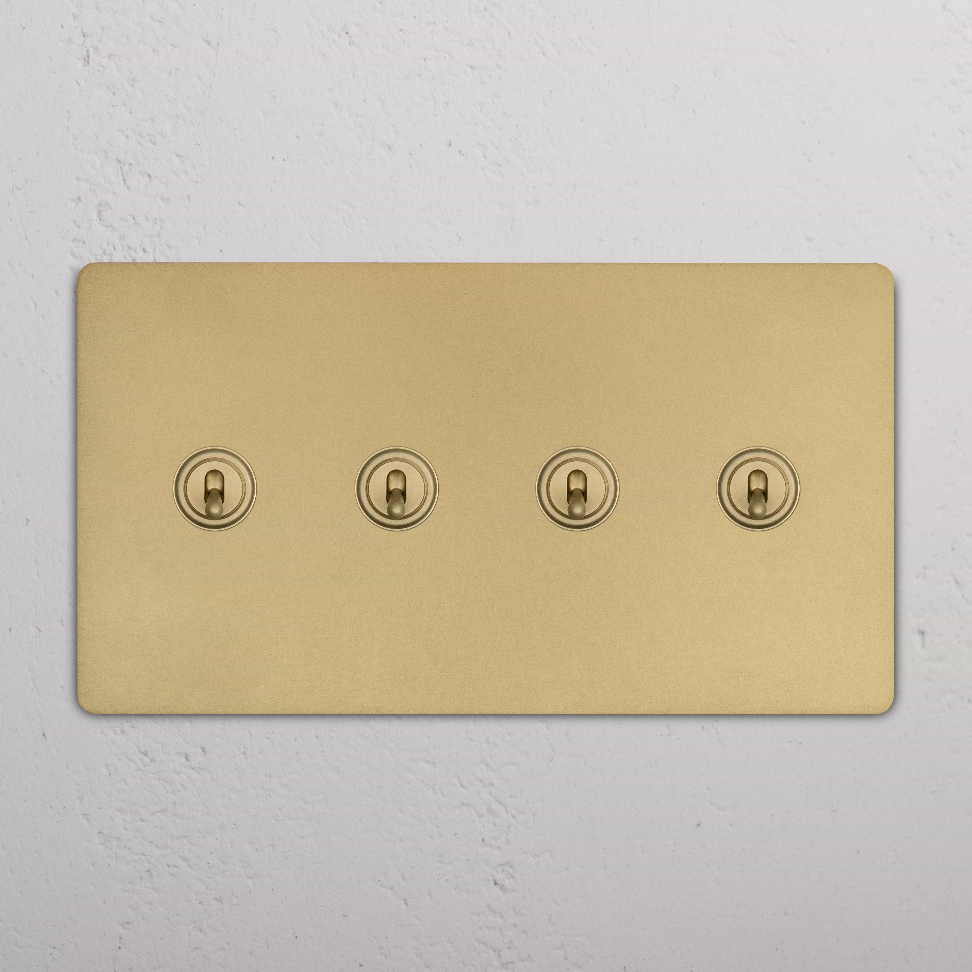 Grove 4G Toggle Switch in antique brass finish with four toggles, mounted on a white wall.