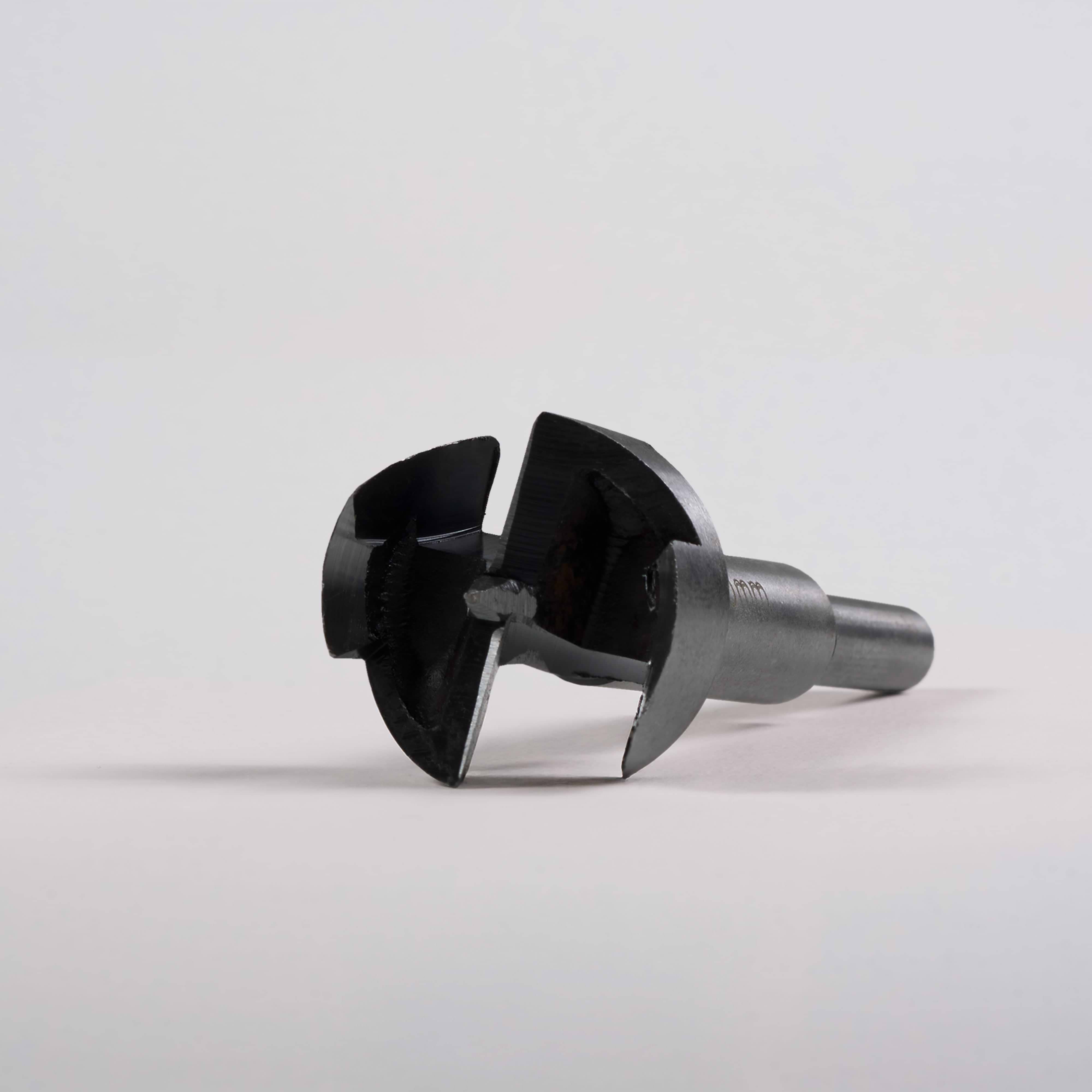 Close-up of a metal Door Handle Installation Drill Bit with sharp, circular cutting edges on a gray surface.