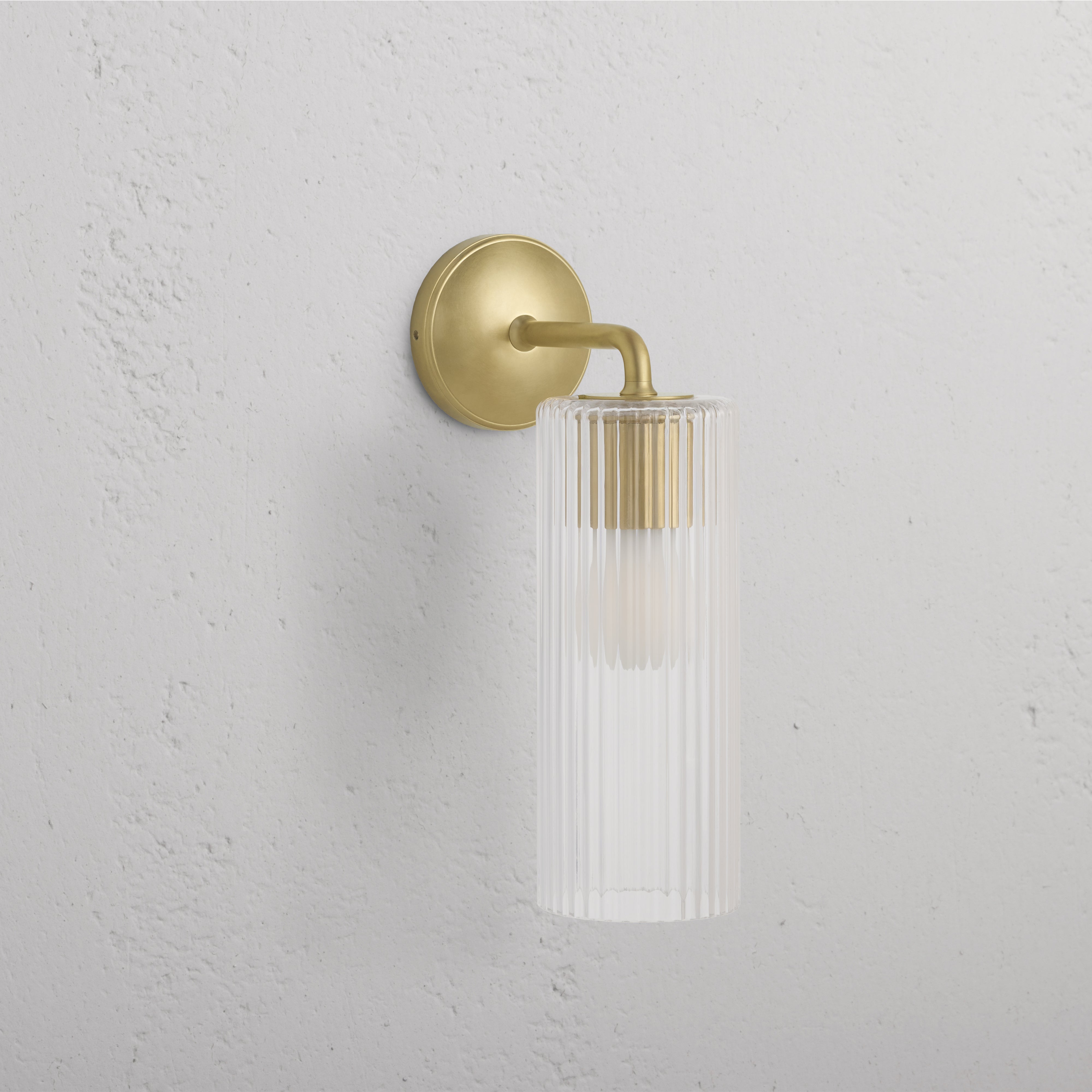 Large Claremont Wall Light with fluted glass shade and antique brass base, mounted on a white wall.