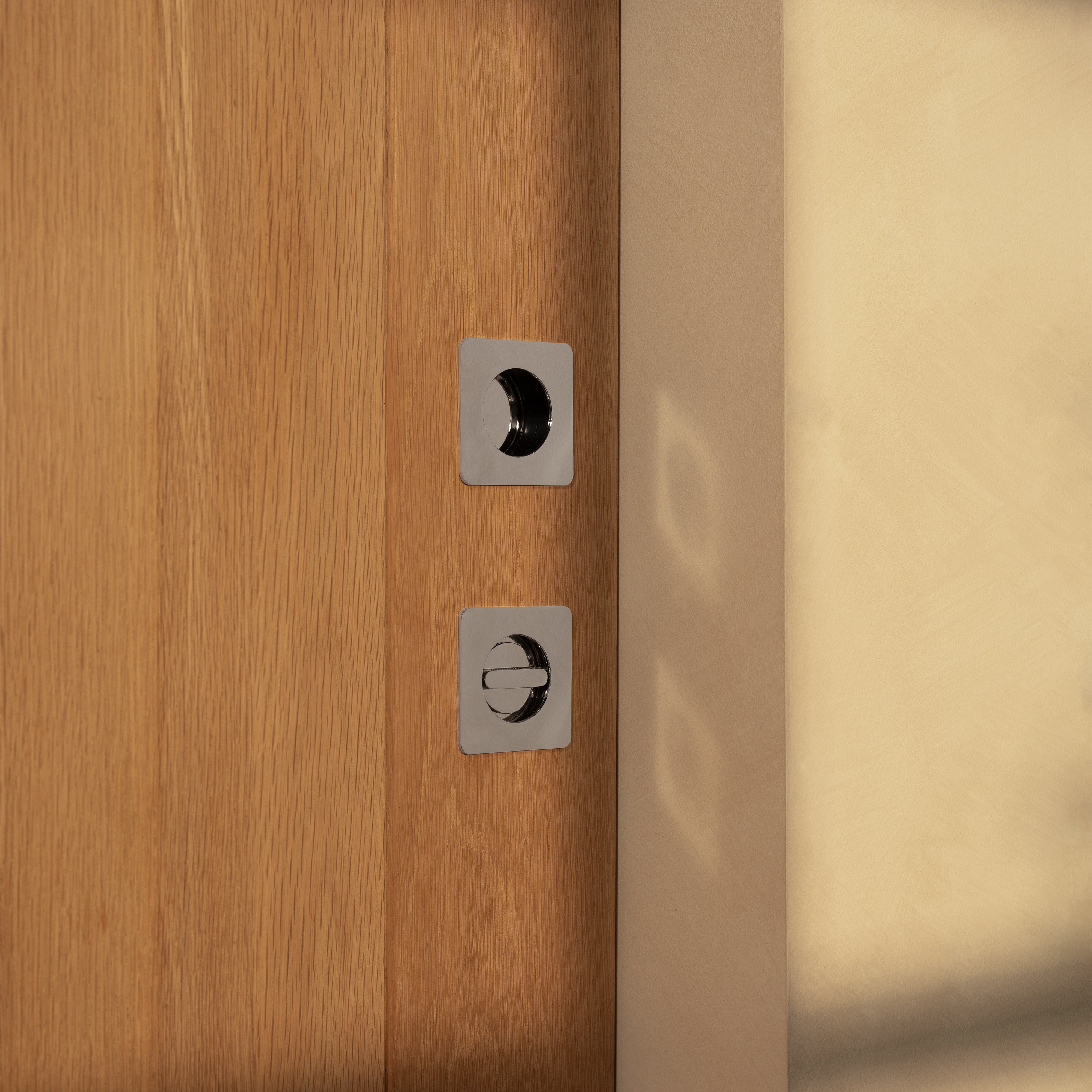 Close-up of a Regent Recessed Small Pull in Polished Nickel installed on a wooden surface.