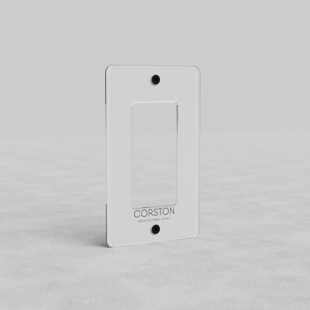 Clear 1-gang outlet plate, rectangular with central cutout and two screw holes, branded Corston at bottom.