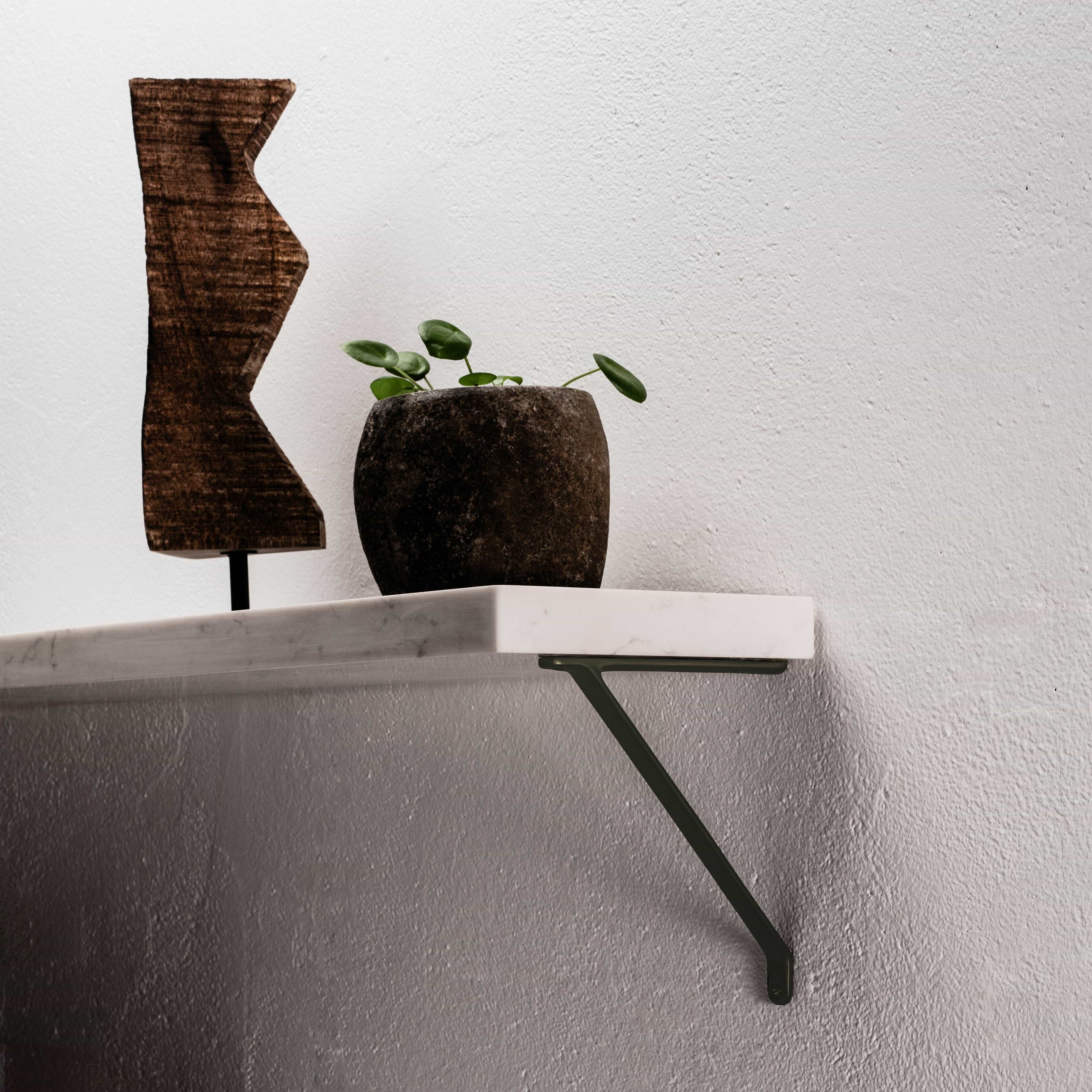 Small bronze Brixton shelf bracket mounted on a wall, supporting a wooden shelf.