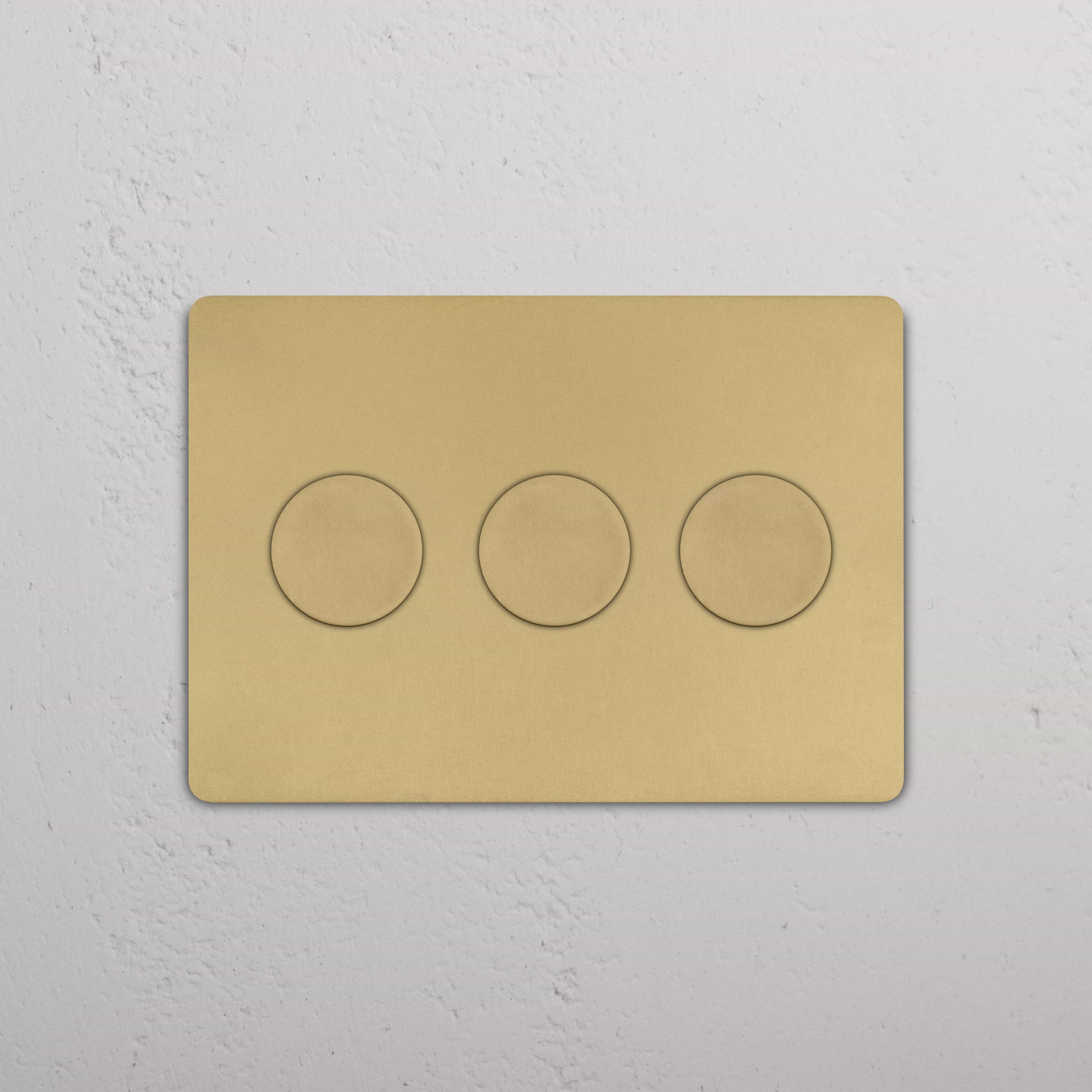 Grove 3G Dimmer Switch in Antique Brass with three round knobs on a gold rectangular plate, wall-mounted.
