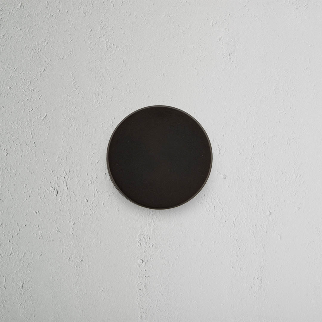 Bronze Onslow Dummy Door Knob Set mounted on a white wall, shown centered with a sleek, round design.