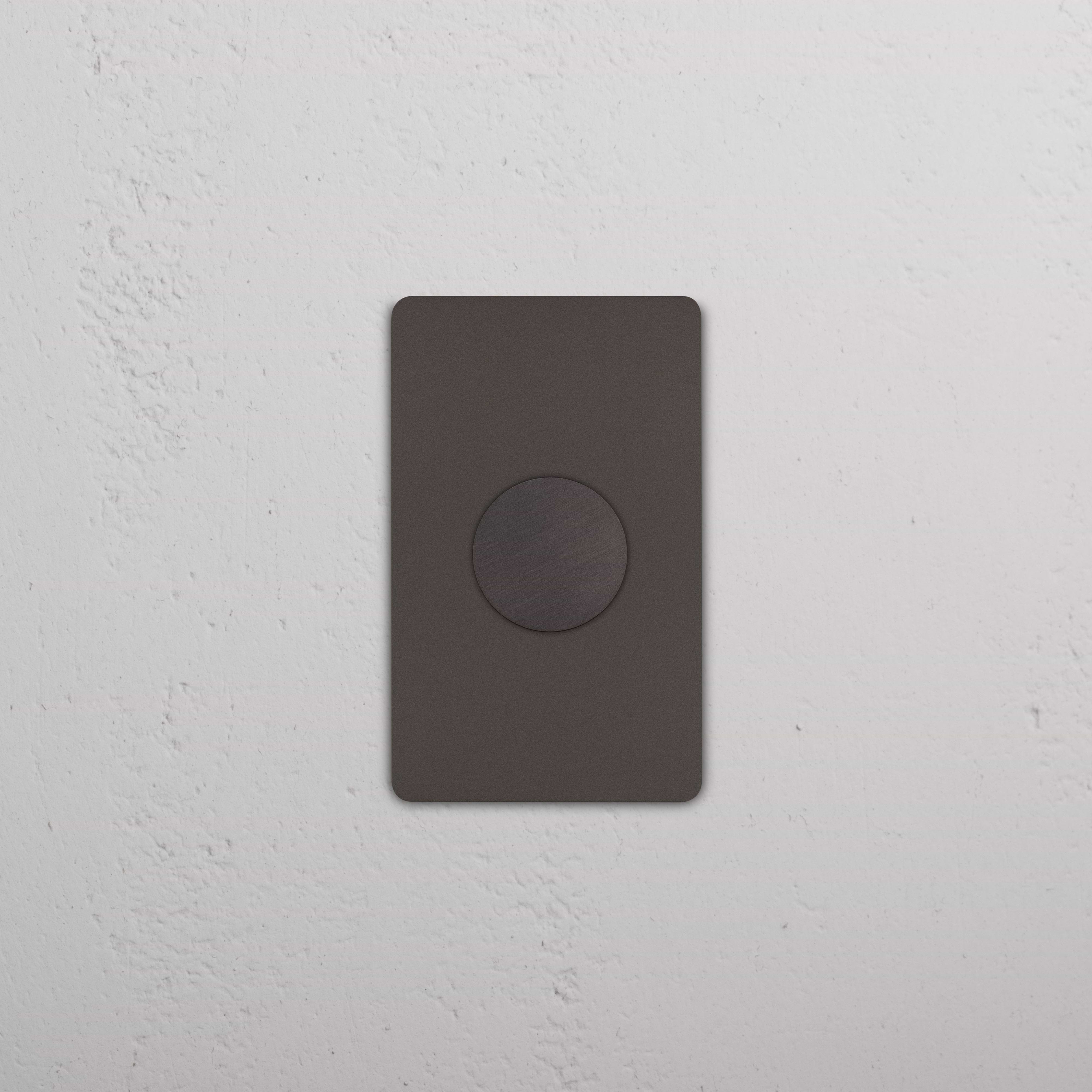 Grove 1G Dimmer Switch in bronze finish, featuring a circular control, installed on a white wall.