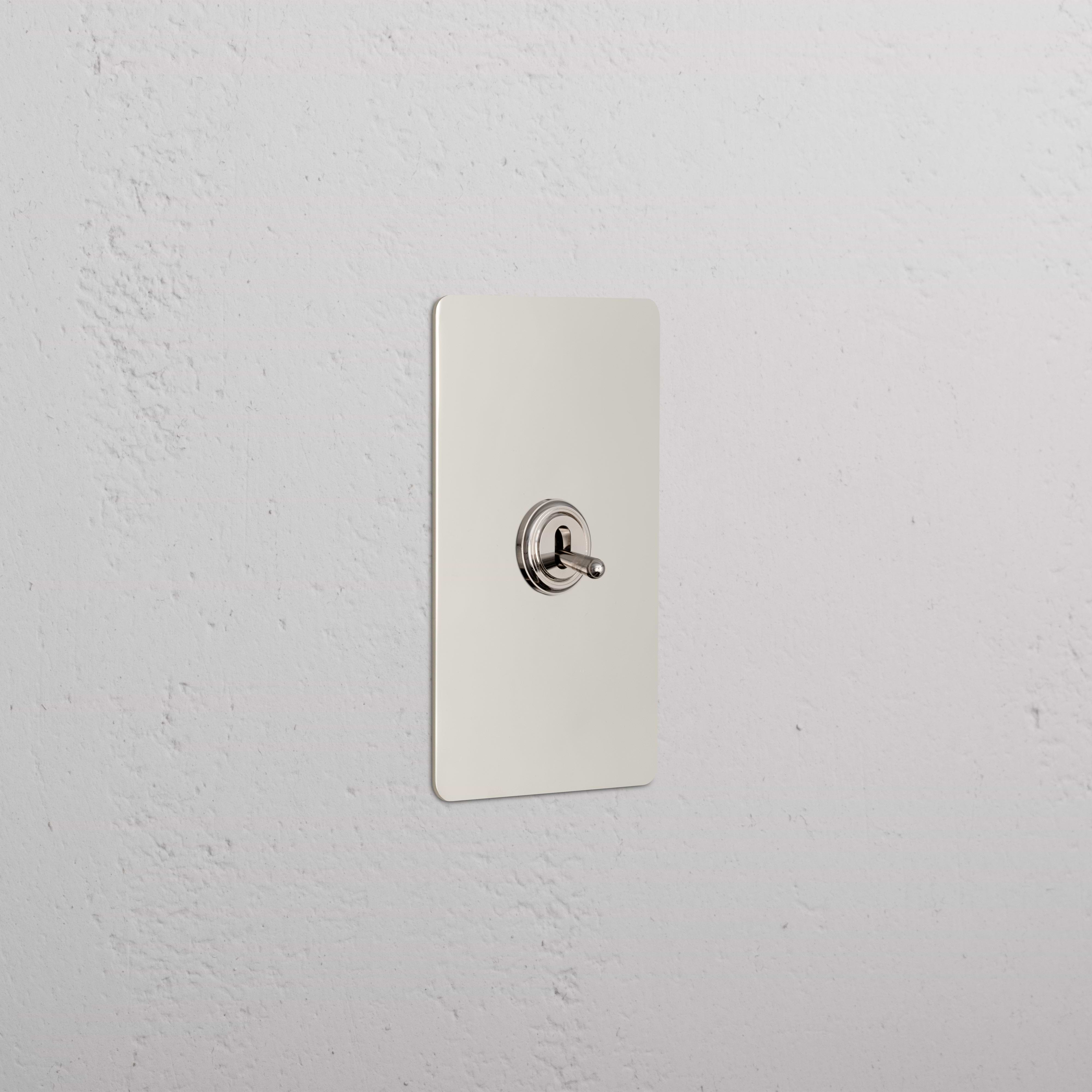 Kew 1G Dimming Retractive Toggle Switch in Polished Nickel, mounted on a white textured wall.
