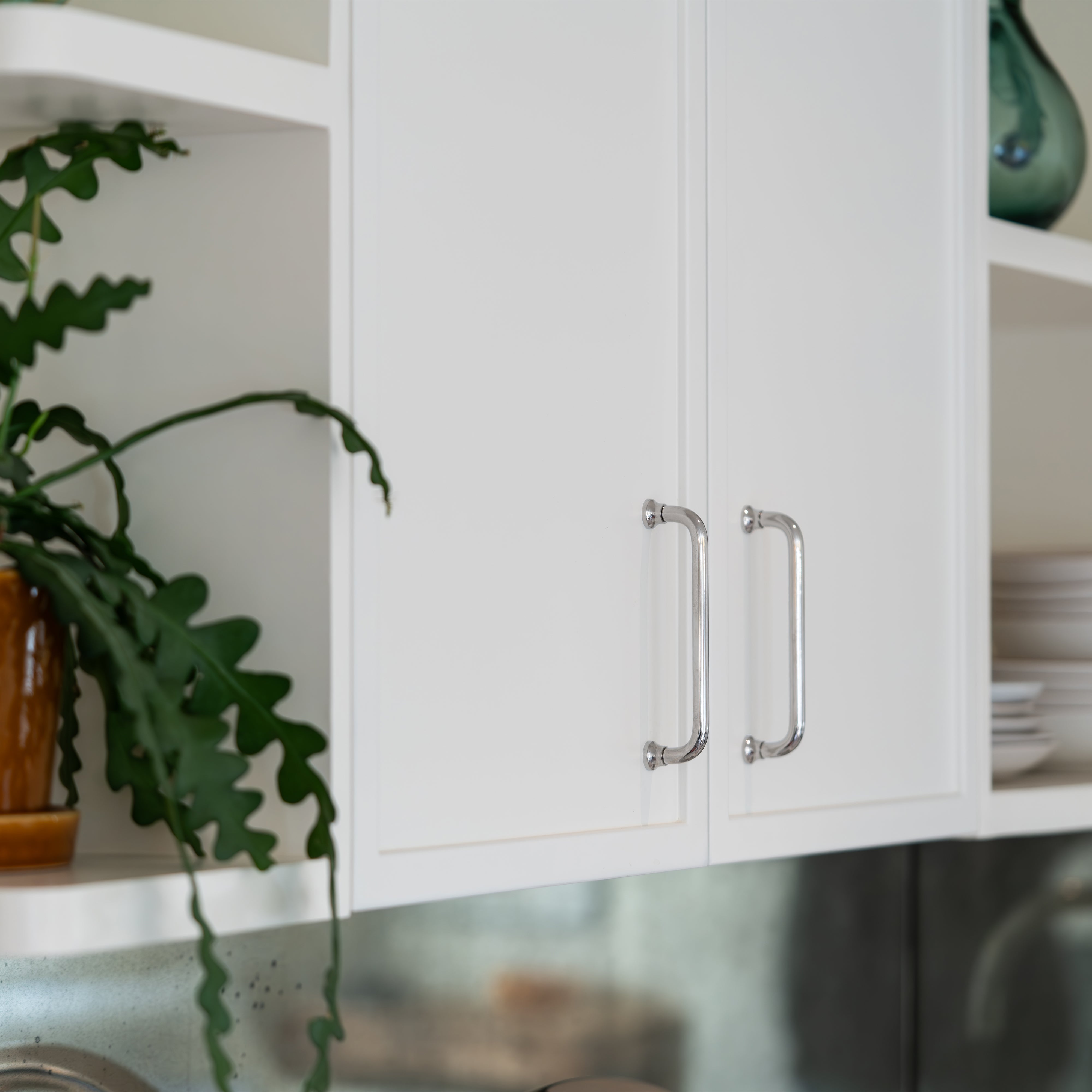 Close-up of a Sycamore Furniture Handle Small in polished nickel finish installed on a cabinet drawer.