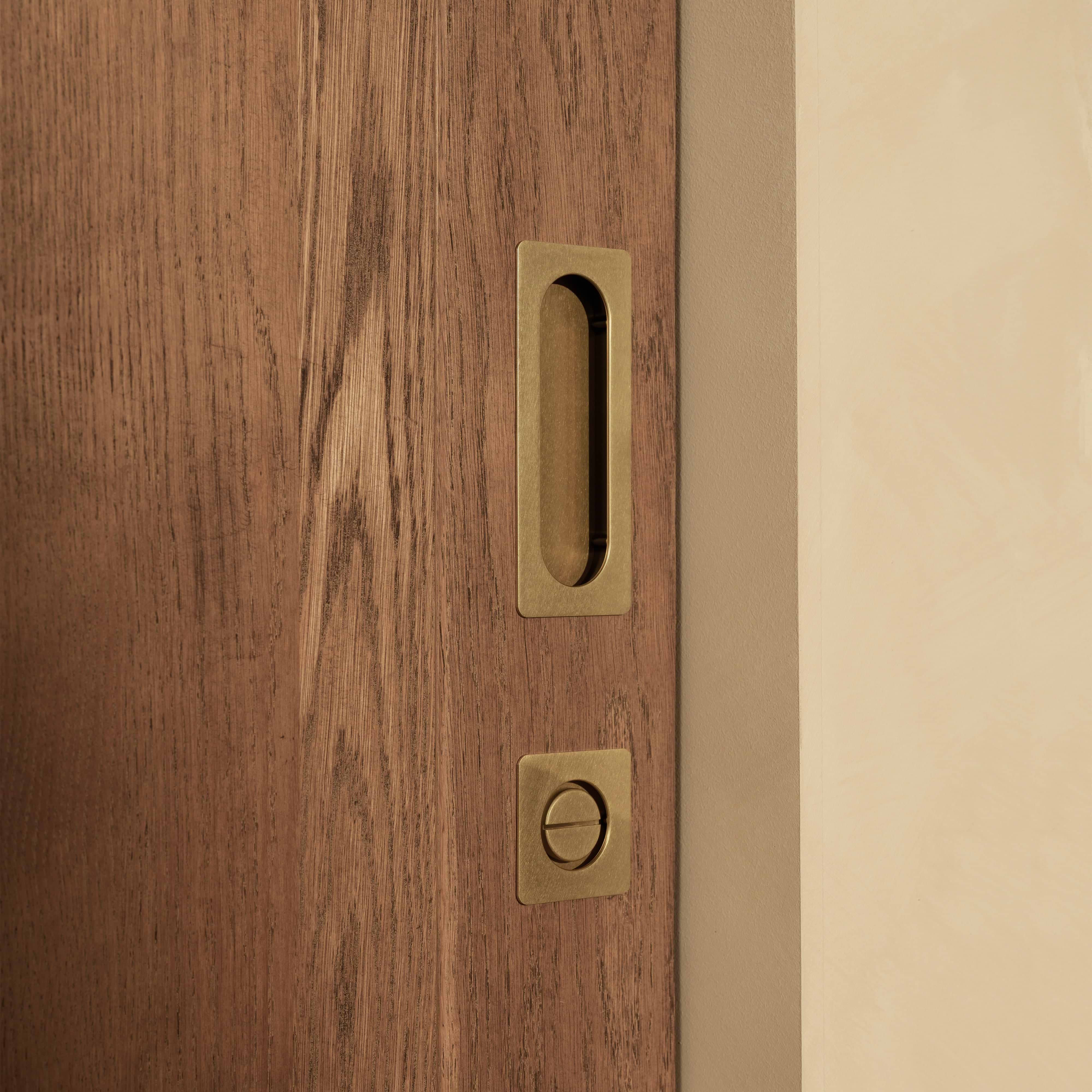 Regent Recessed Medium Pull in Antique Brass fitted on a wooden sliding door, shown without unrelated features.