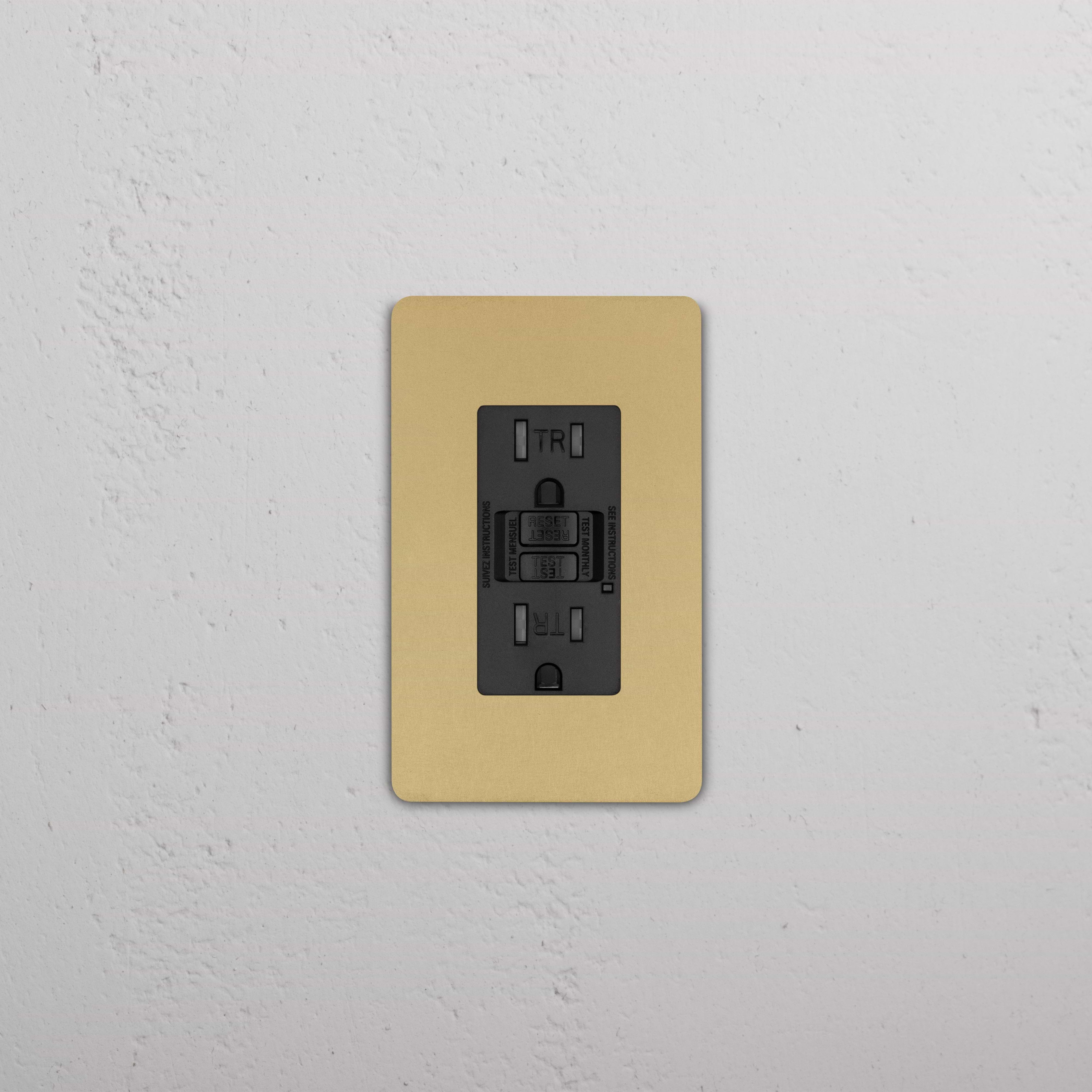 Grove 1G 15A GFCI Outlet in black with antique brass cover plate, installed on a white wall.