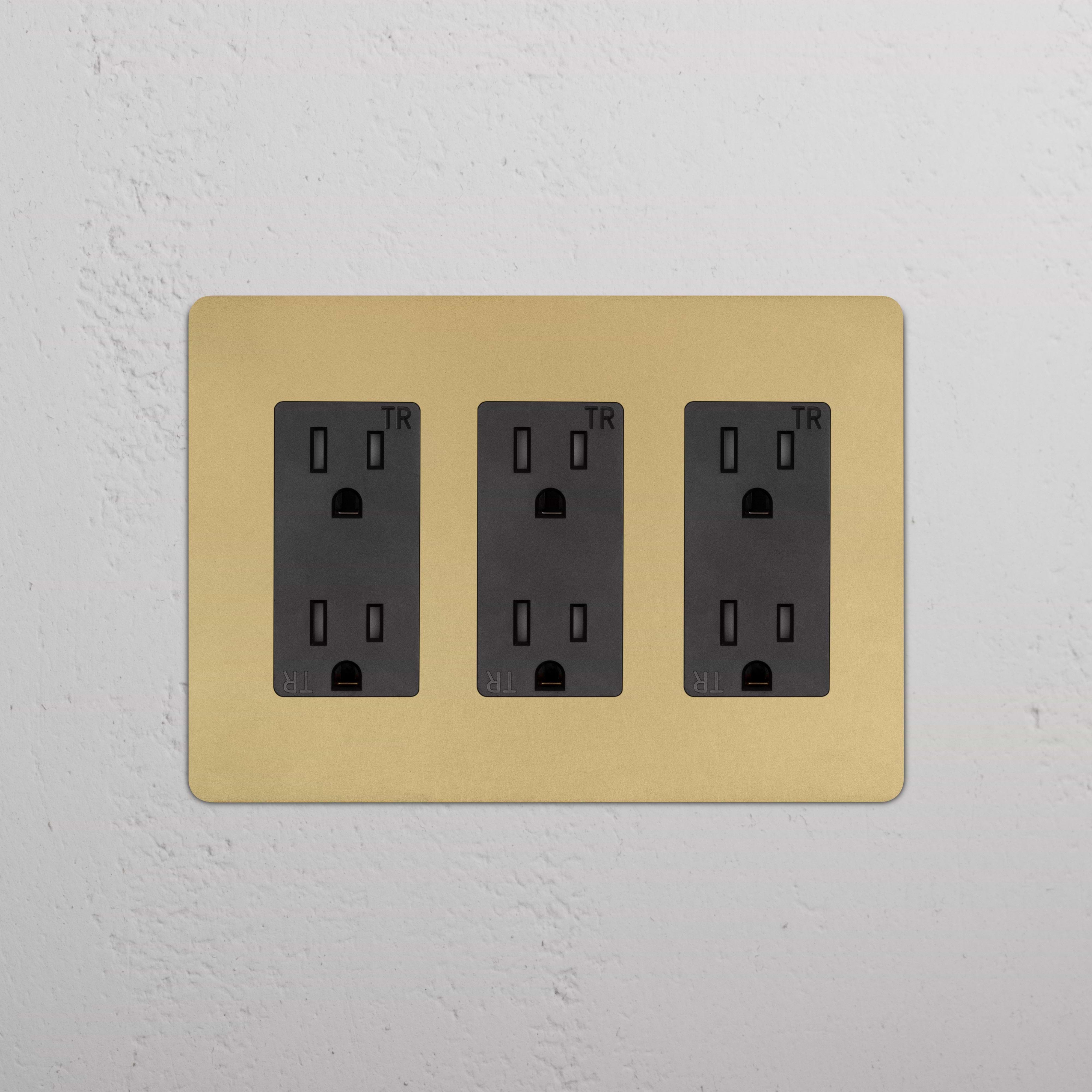 Kew 3G Outlet in Antique Brass Black with three black sockets, mounted on a white textured wall.
