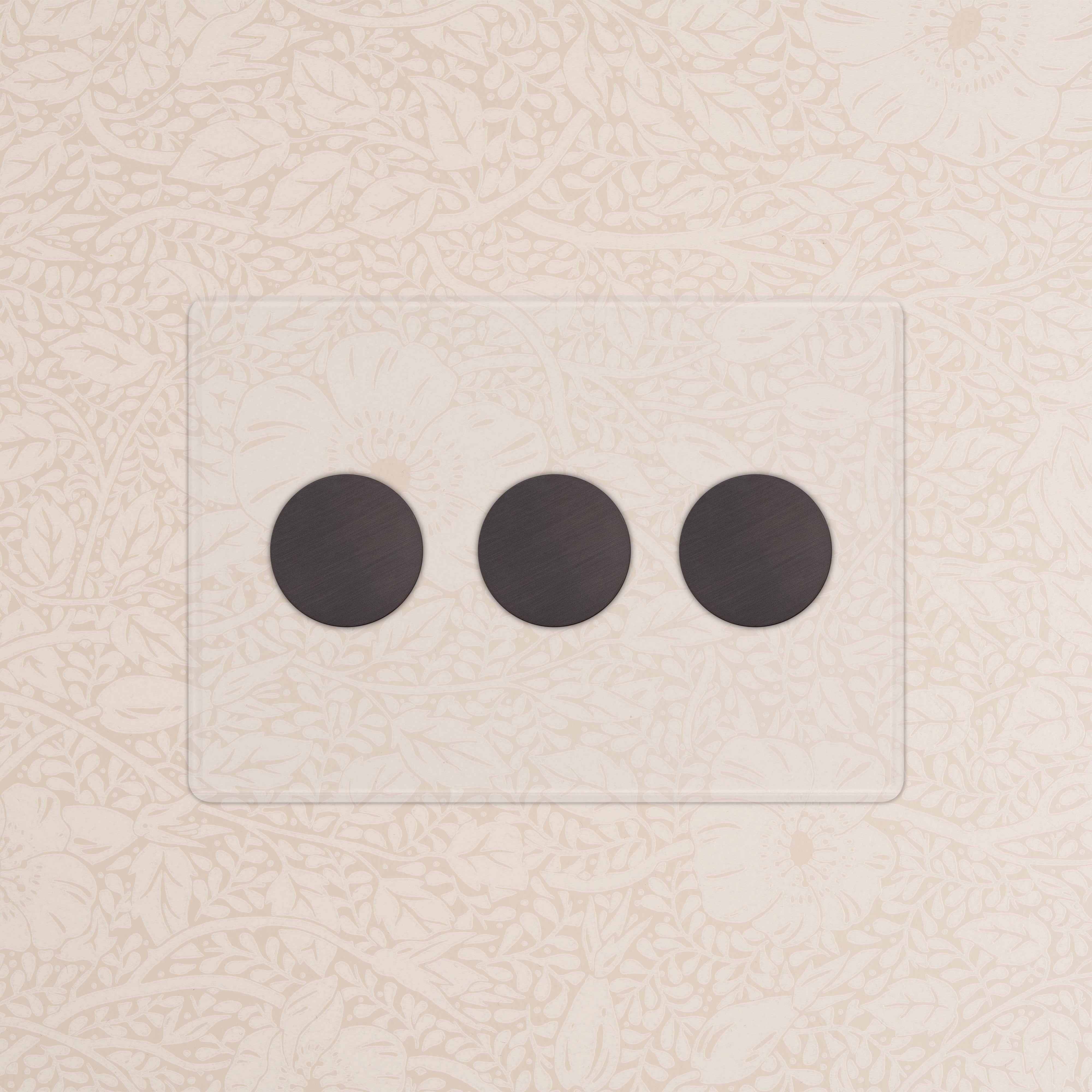 Kew 3G Dimmer Switch - Clear Bronze with three round black dials on beige floral-patterned wallpaper.