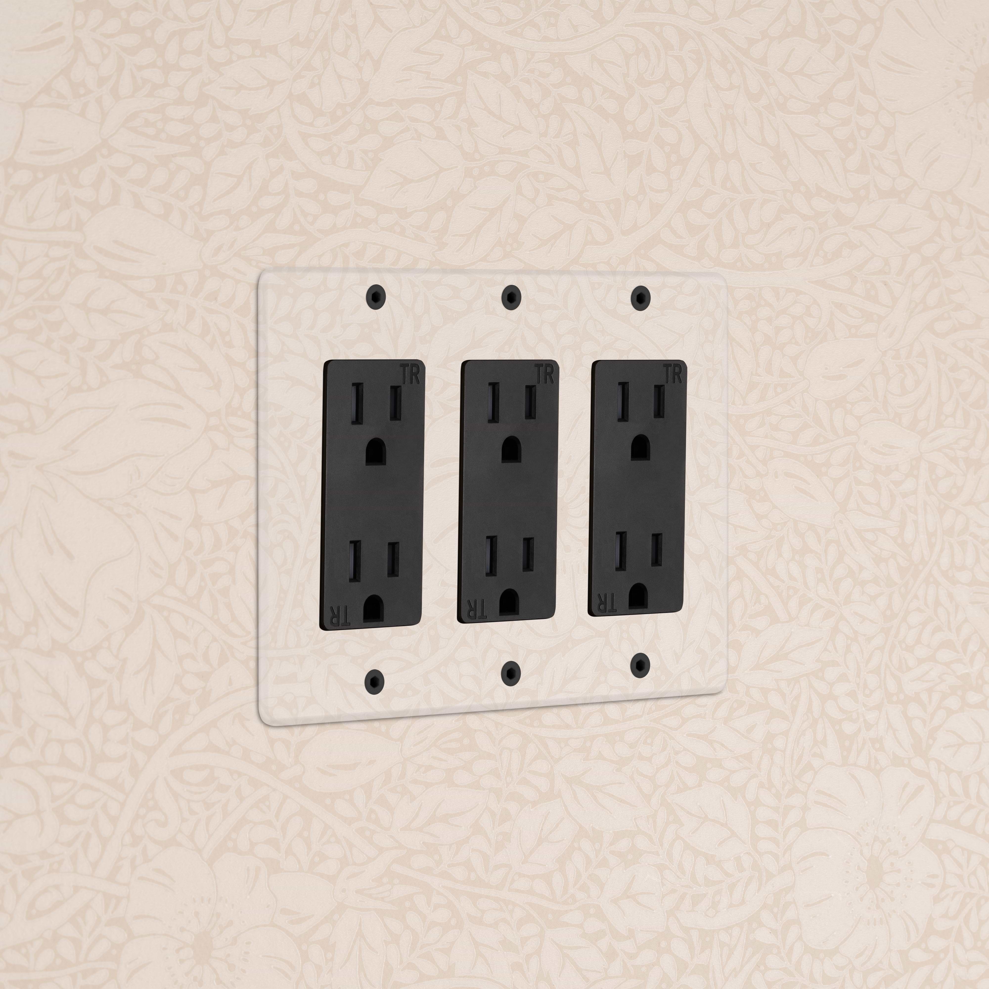 Kew 3G Outlet in clear black finish mounted on a white faceplate against a floral cream wall.