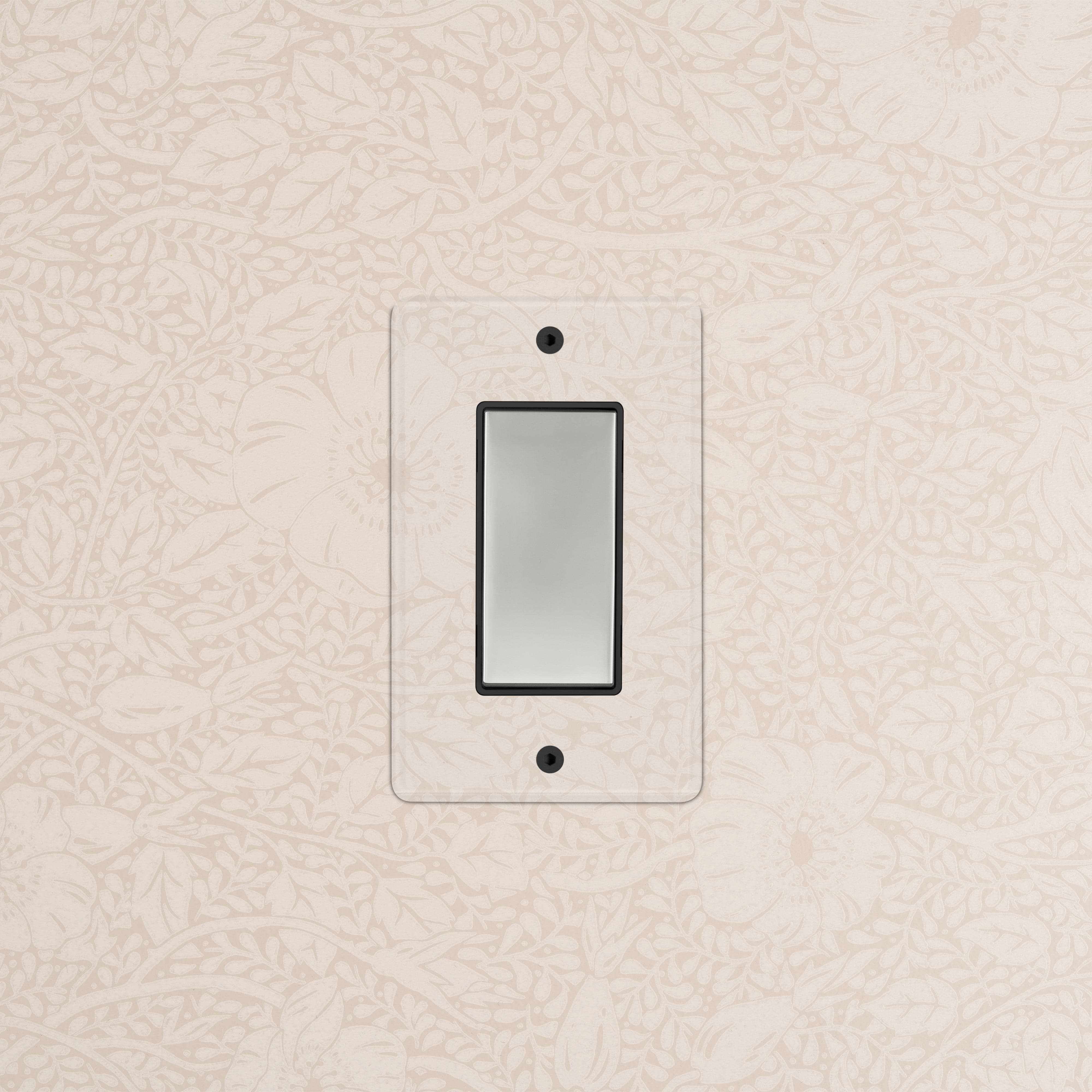 Kew 1G Double Pole Rocker Switch in clear polished nickel with black rocker, shown on a patterned beige wall.