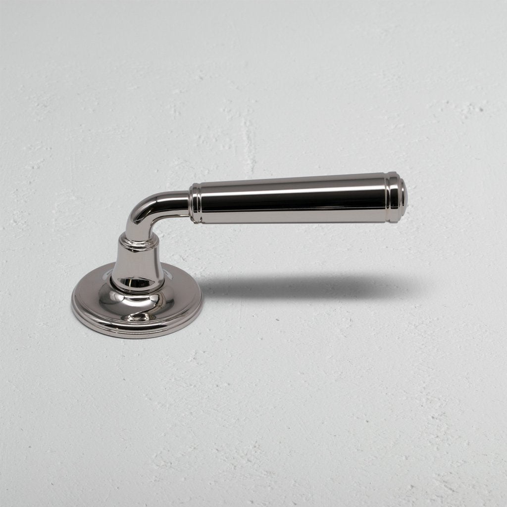 Polished nickel Digby Passage Door Handle Unsprung with rounded base and cylindrical grip on a light wall.