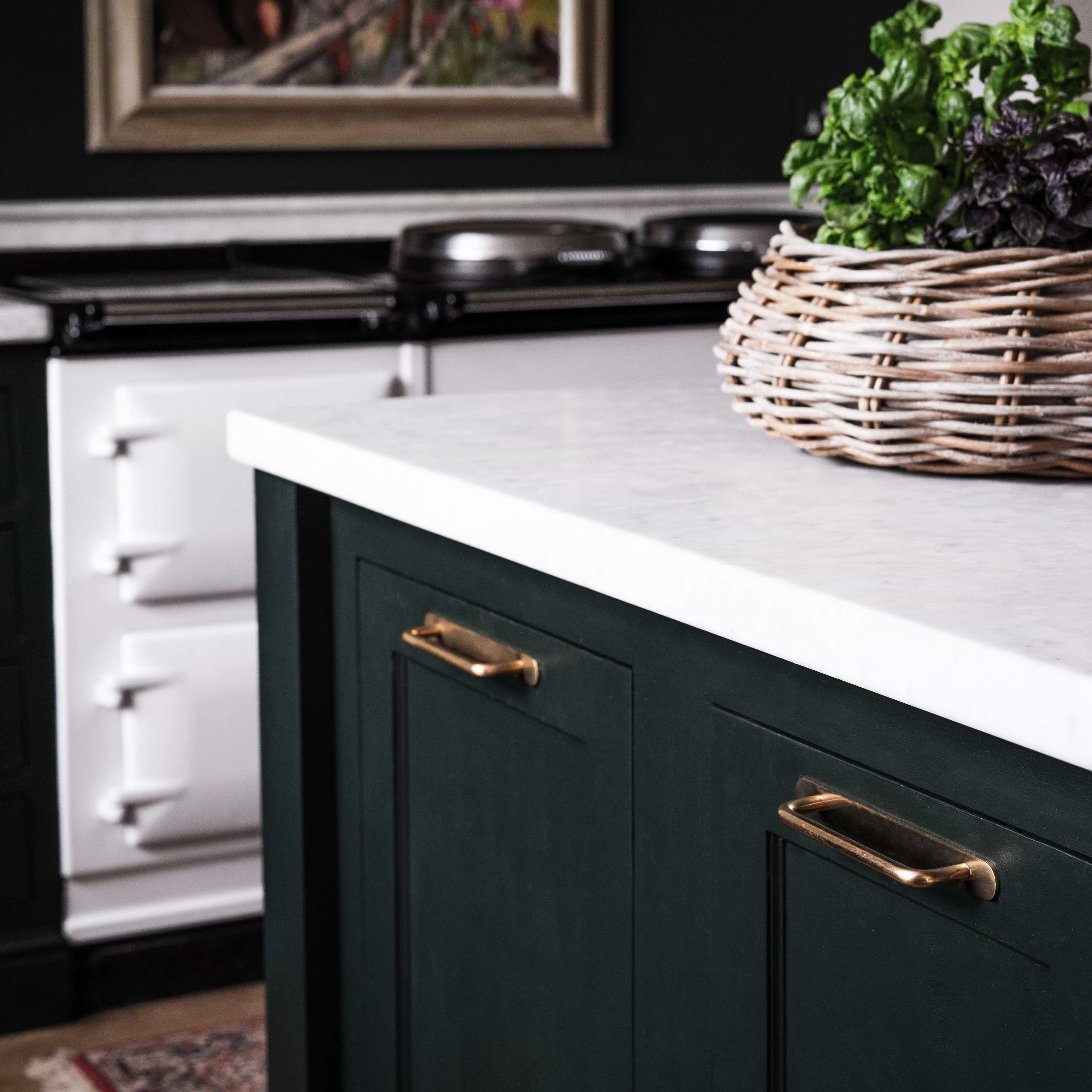 Close-up of a Kilburn Furniture Handle Medium in antique brass fitted on a green cabinet drawer.