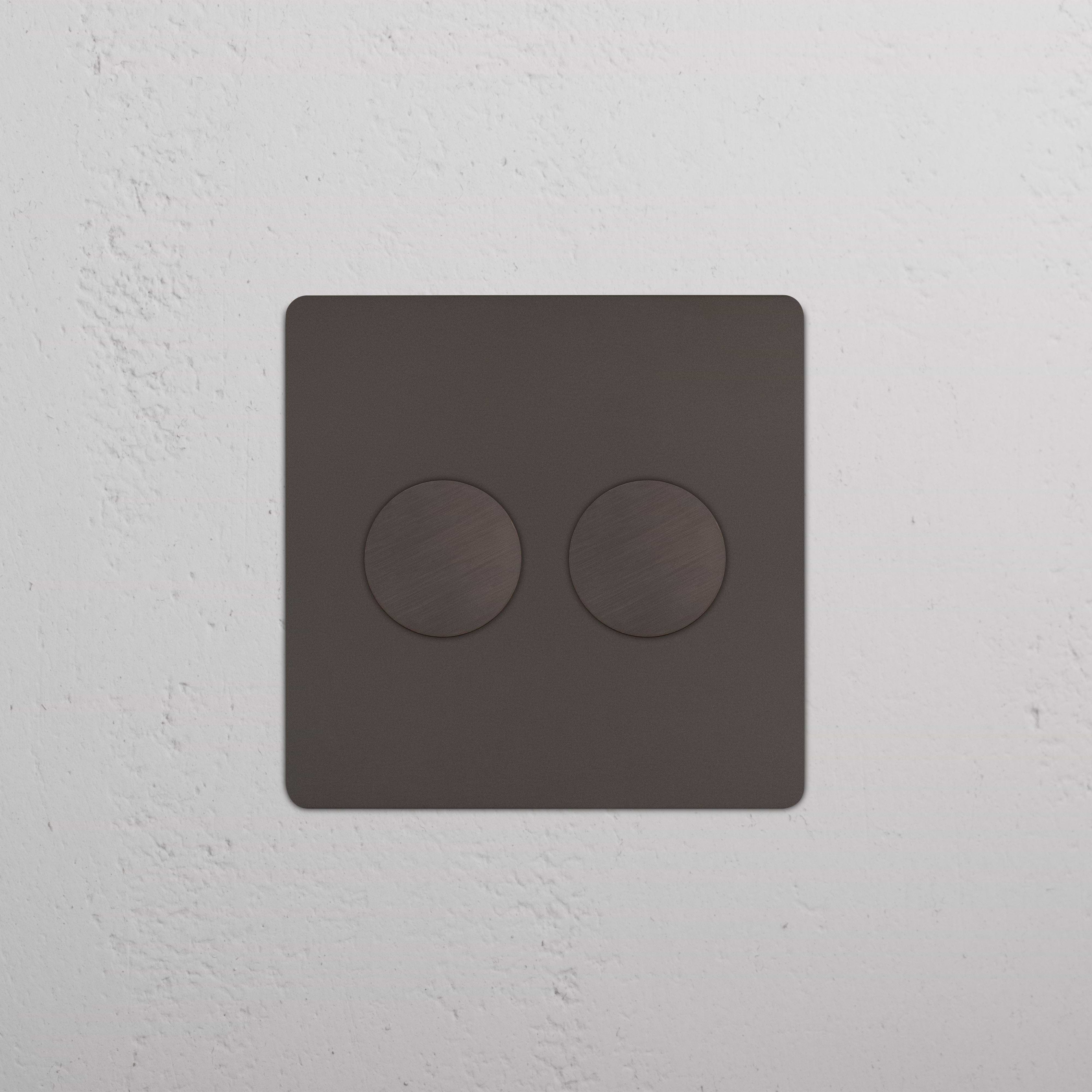 Kew 2G Dimmer Switch in bronze finish with two round controls, installed on a white wall.